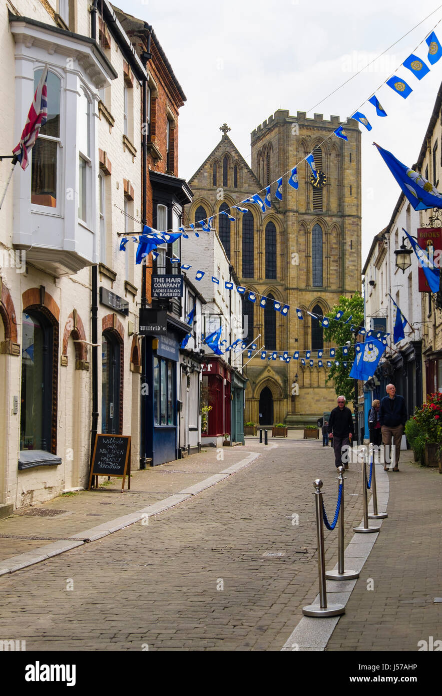 Blick auf die Kathedrale entlang einer schmalen gepflasterten Straße. Kirkgate, Ripon, North Yorkshire, England, UK, Großbritannien Stockfoto