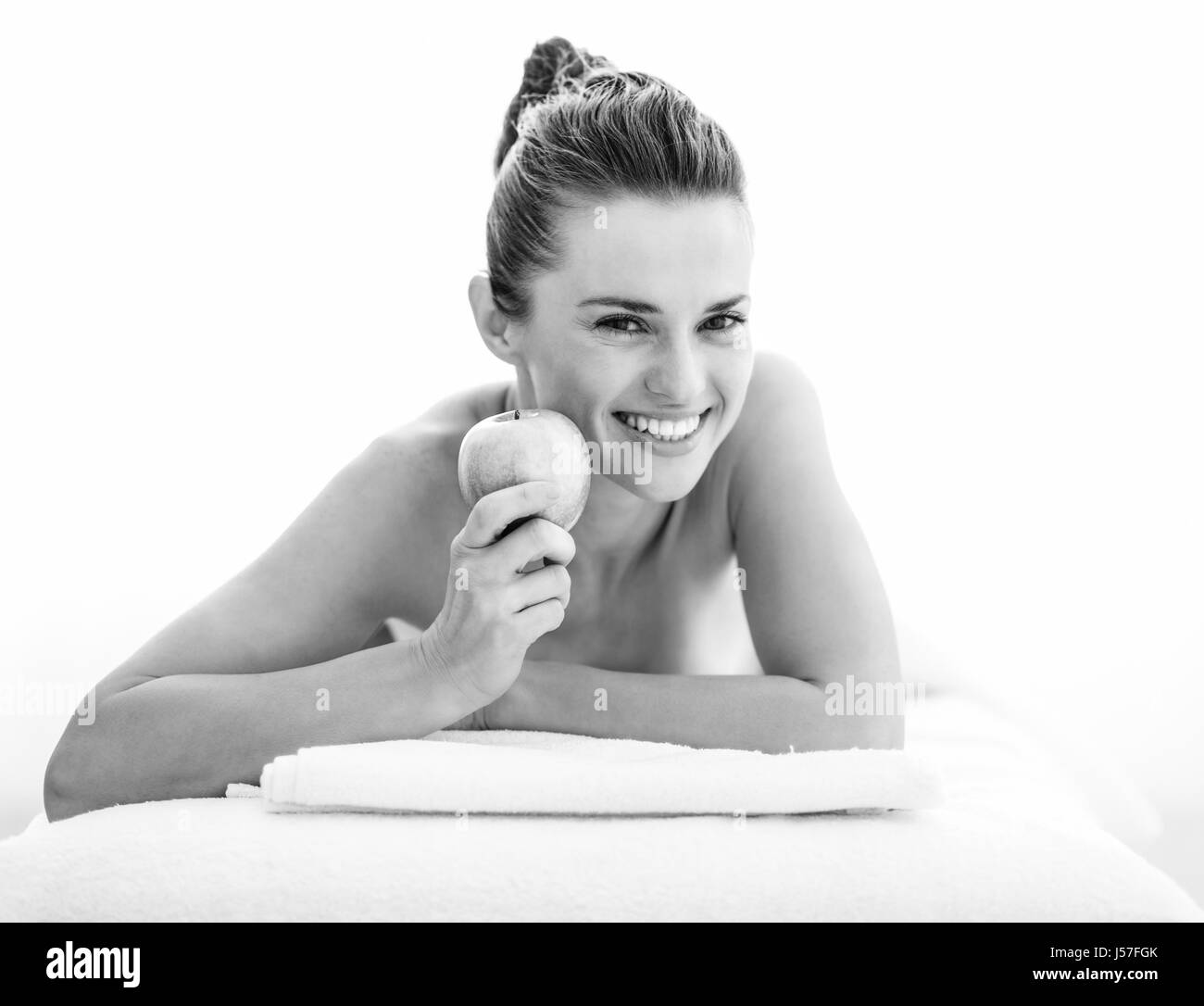 Porträt der lächelnde junge Frau zeigt Apple während der Verlegung auf Massagetisch Stockfoto