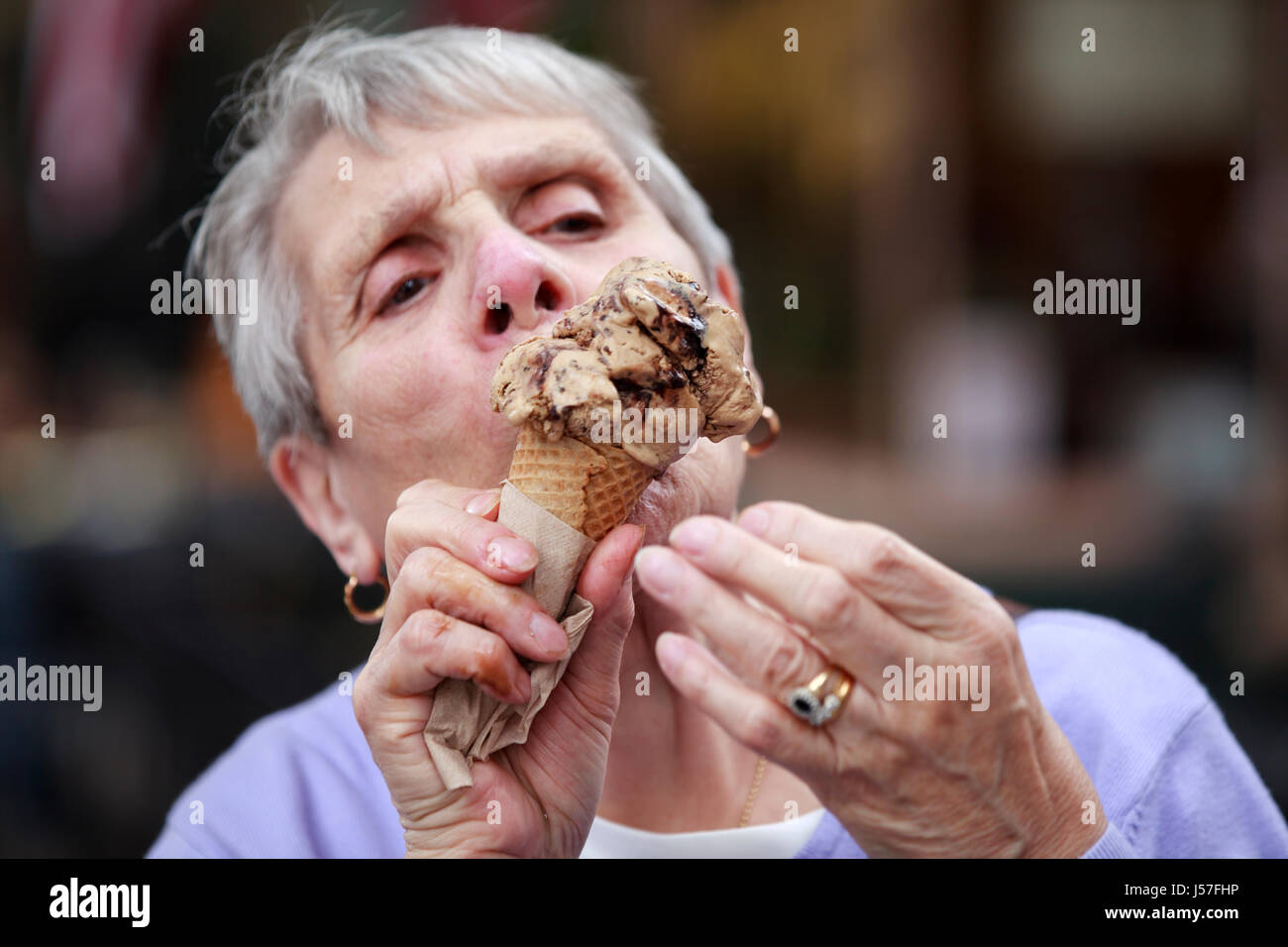 Belmar NJ, USA. Eine ältere Dame oder Seniorin genießt ein großes Eis in einem Kegel. Sie leckt das schmelzende Eis, bevor es aus dem Kegel fällt Stockfoto