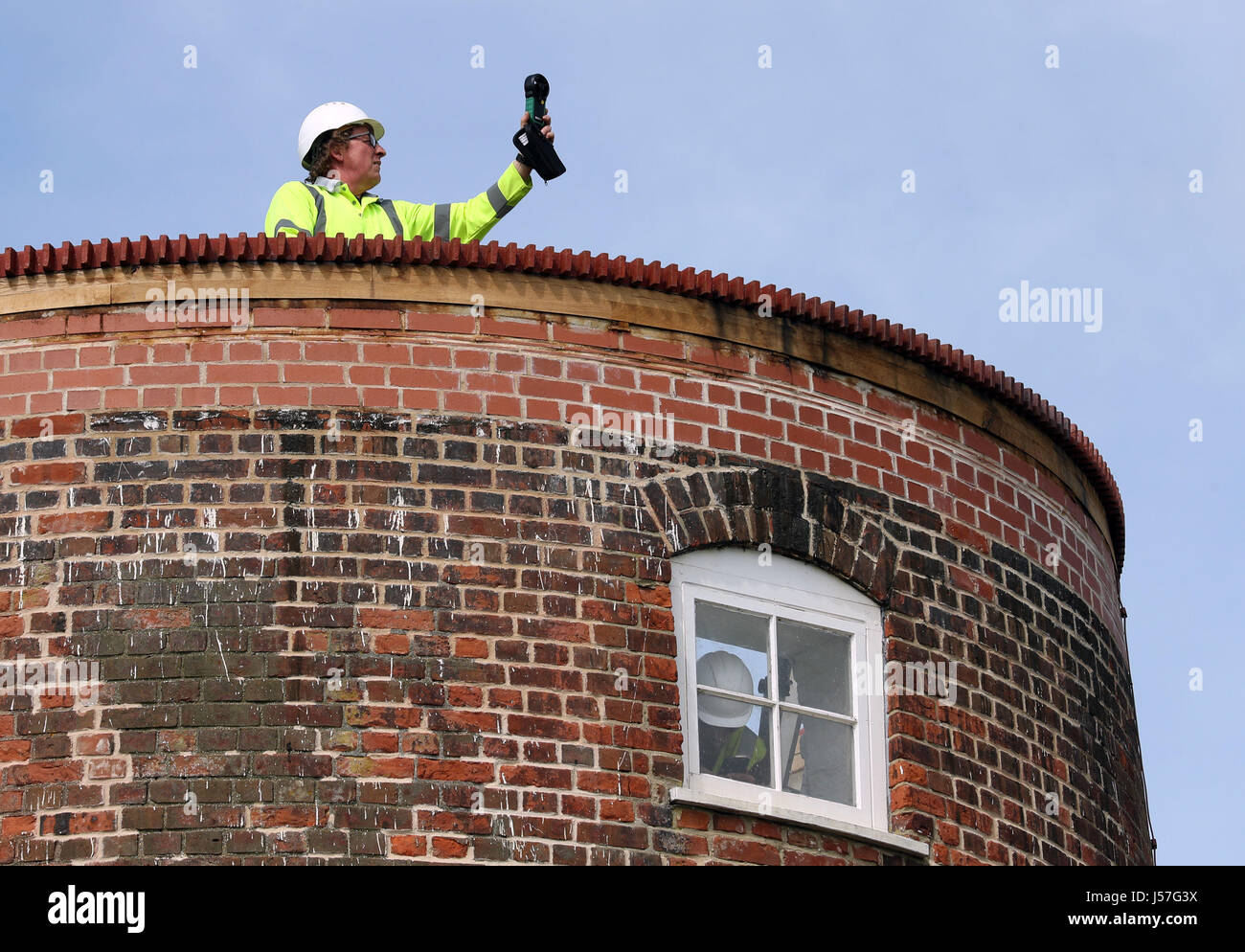 Ein Arbeiter prüft die Windgeschwindigkeit, bevor ein Kran die Dach-Kappe des Horsey Windpumpe einrasten auf den oberen Teil des National Trust Horsey Windpumpe in Horsey, Great Yarmouth hebt. Stockfoto