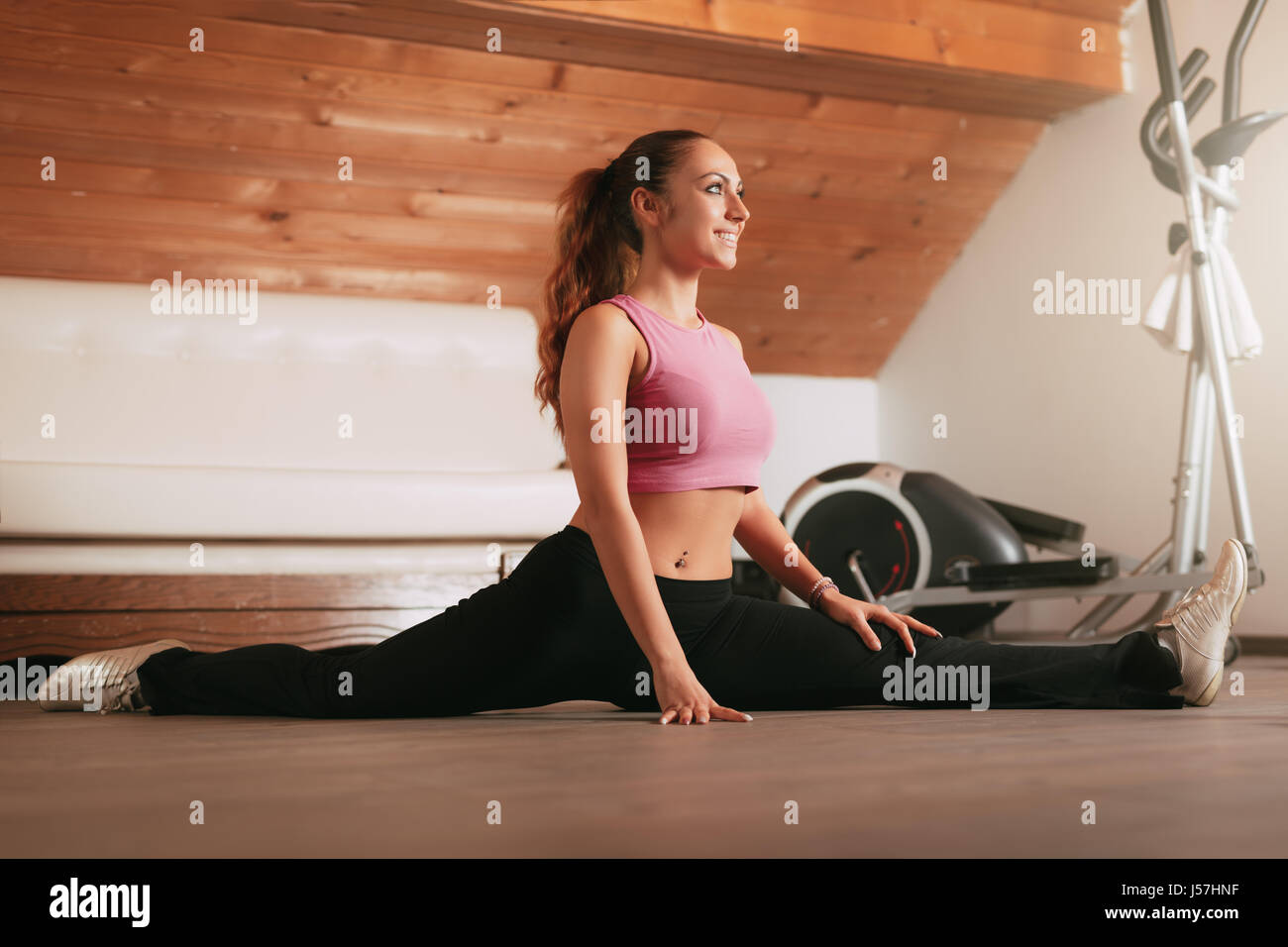 Schöne junge Frau dabei spaltet Übungen in der Wohnung. Stockfoto