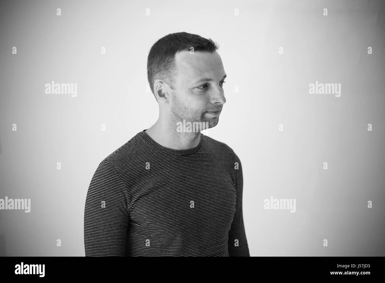 Studioportrait Profil der jungen Erwachsenen europäischen Mann über weiße Wand stehen. Schwarz / weiß Stockfoto