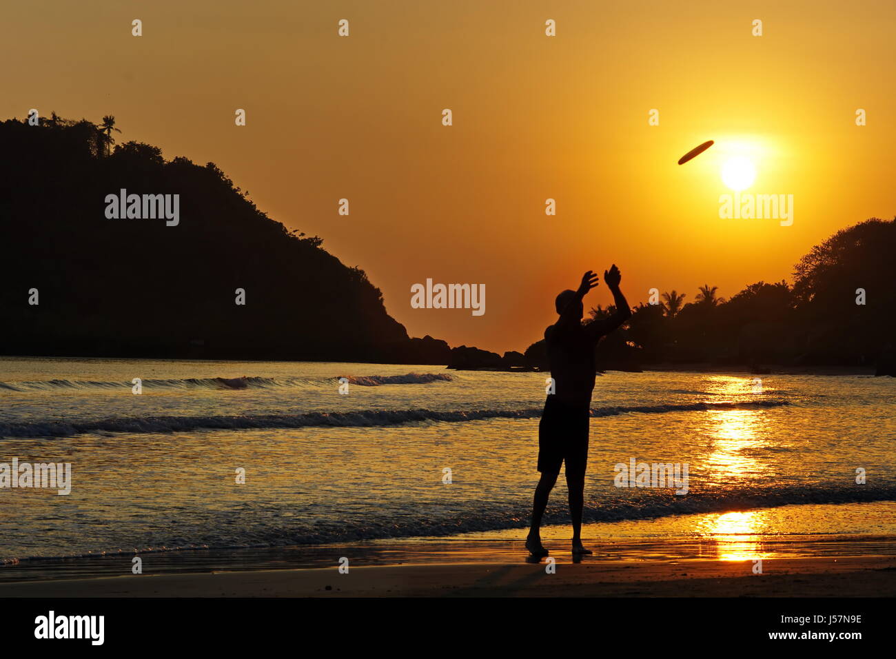 Mann spielt Frisbee Palolem Beach, Süd-Indien, Goa, Arambol, Agonda Anjuna, Cola Meer bei Sonnenuntergang Stockfoto