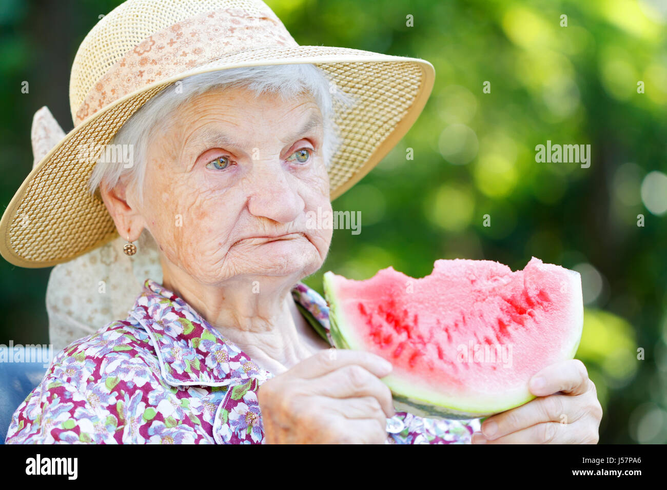 Gerne ältere Frau essen Wassermelone im Garten Stockfoto