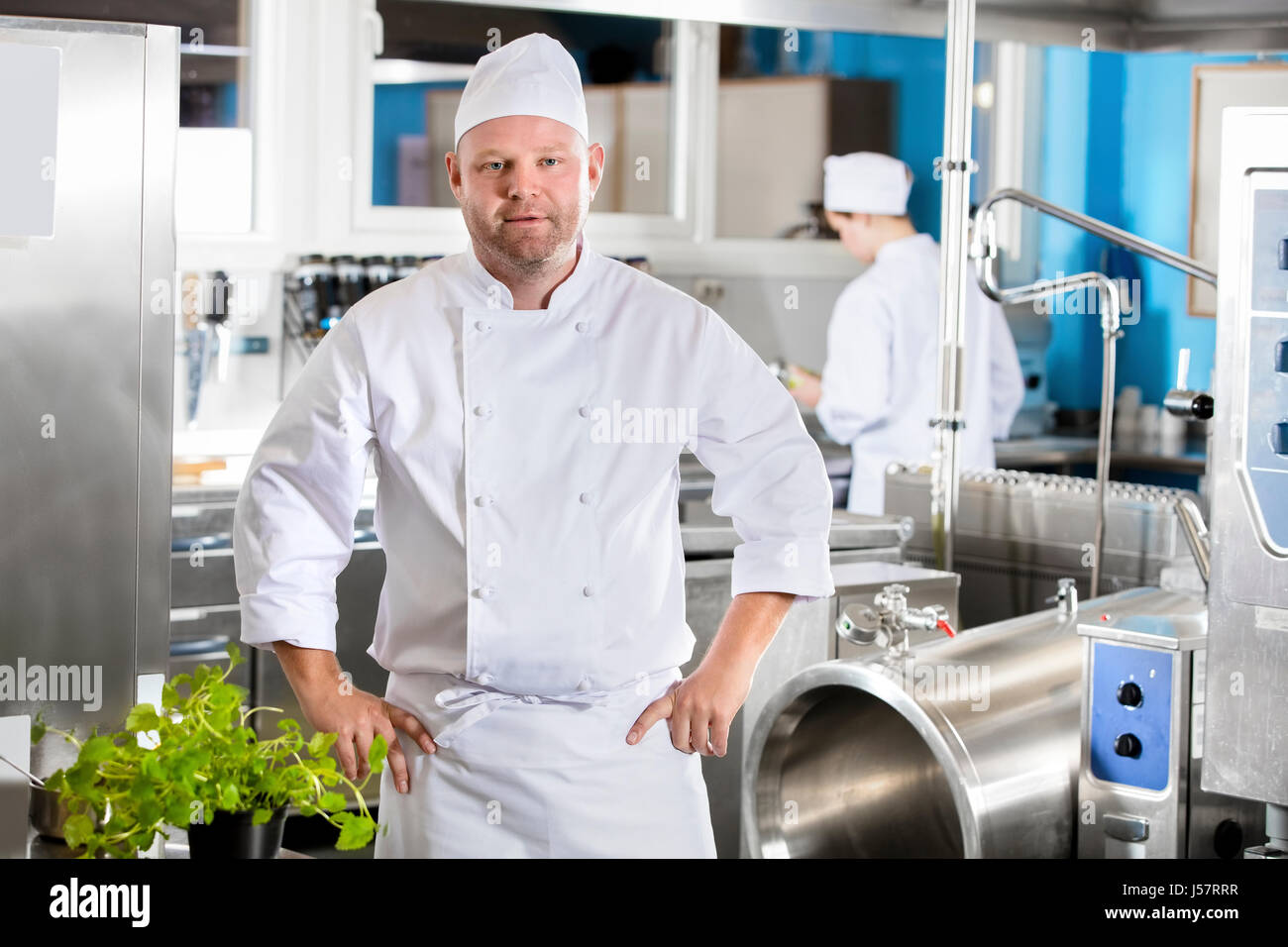 Porträt von zuversichtlich und lächelnd Chef Zubereitung von Essen in großen Küche Stockfoto