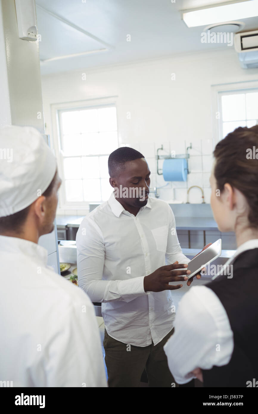 Männliche Restaurantleiter mit digital-Tablette beim Briefing sein Küchenpersonal in der Großküche Stockfoto
