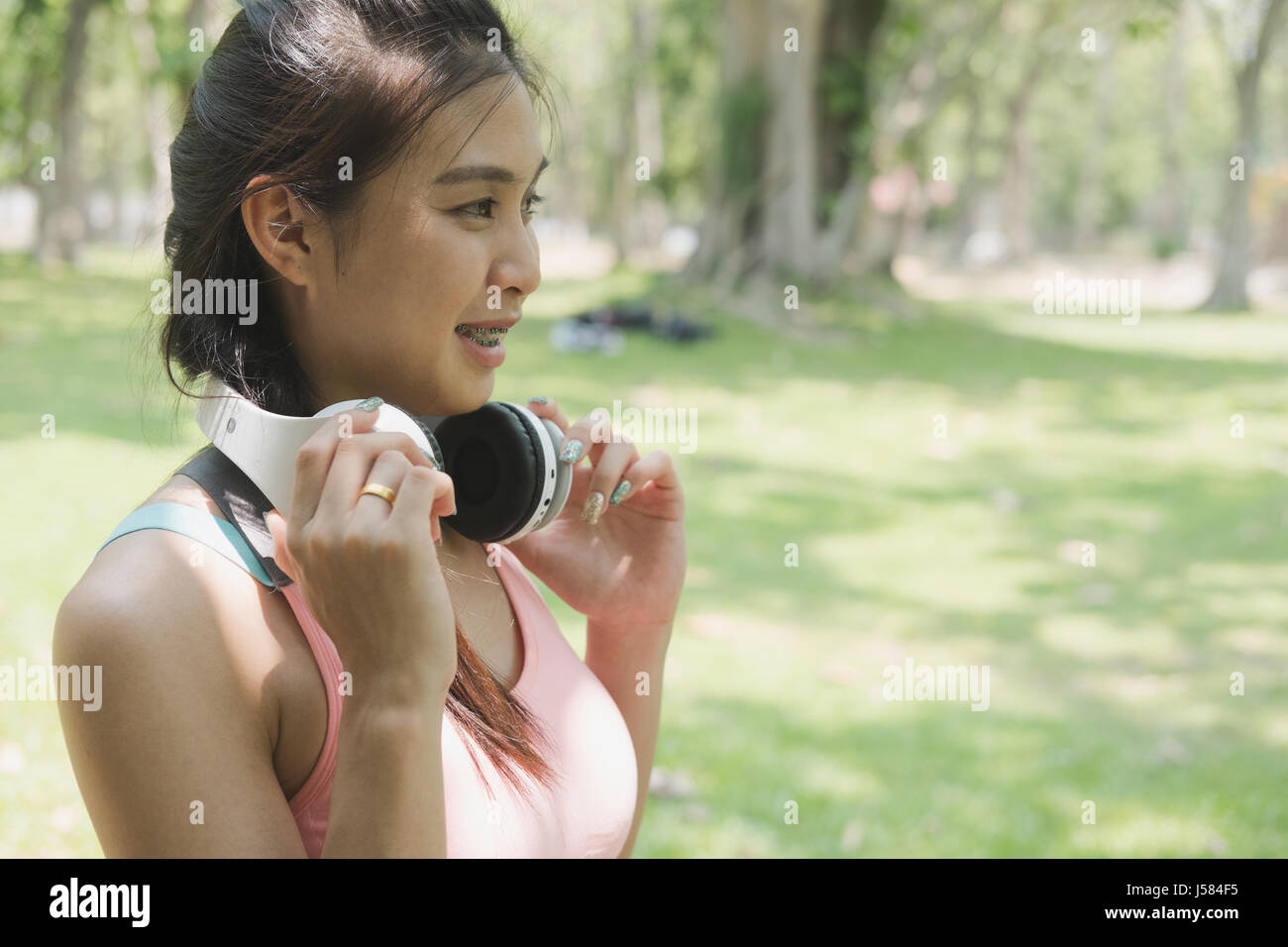 junge schöne asiatische Fitness Sportler Frau mit weißen Kopfhörer ein jogging im Sommerpark vorbereiten. Stockfoto