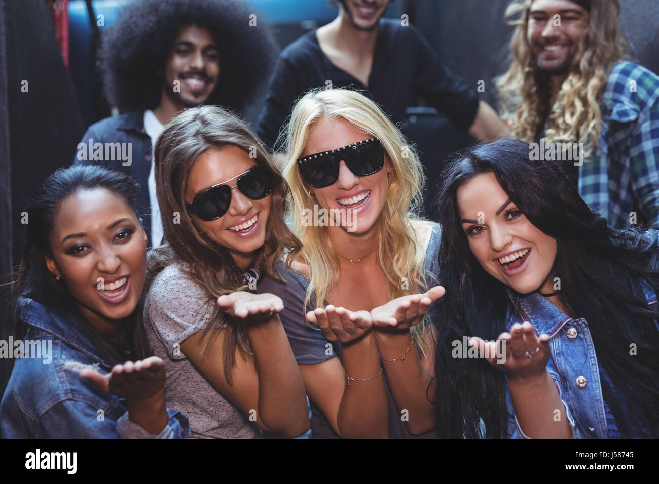 Porträt von Frauen mit männlichen Freunden im Hintergrund im Nachtclub Stockfoto