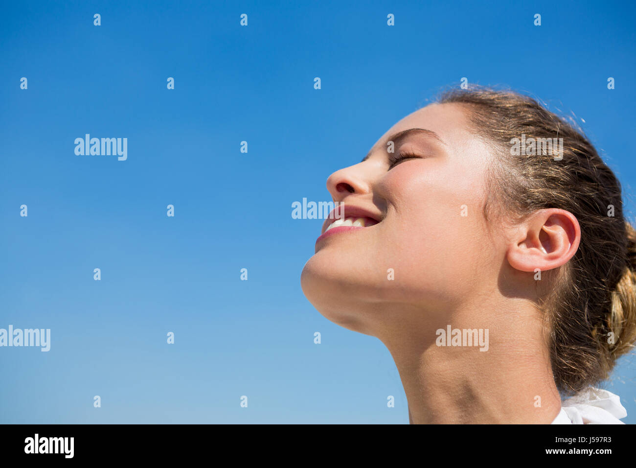 Niedrigen Winkel Ansicht der lächelnde Frau mit Kopf nach hinten gegen blauen Himmel Stockfoto