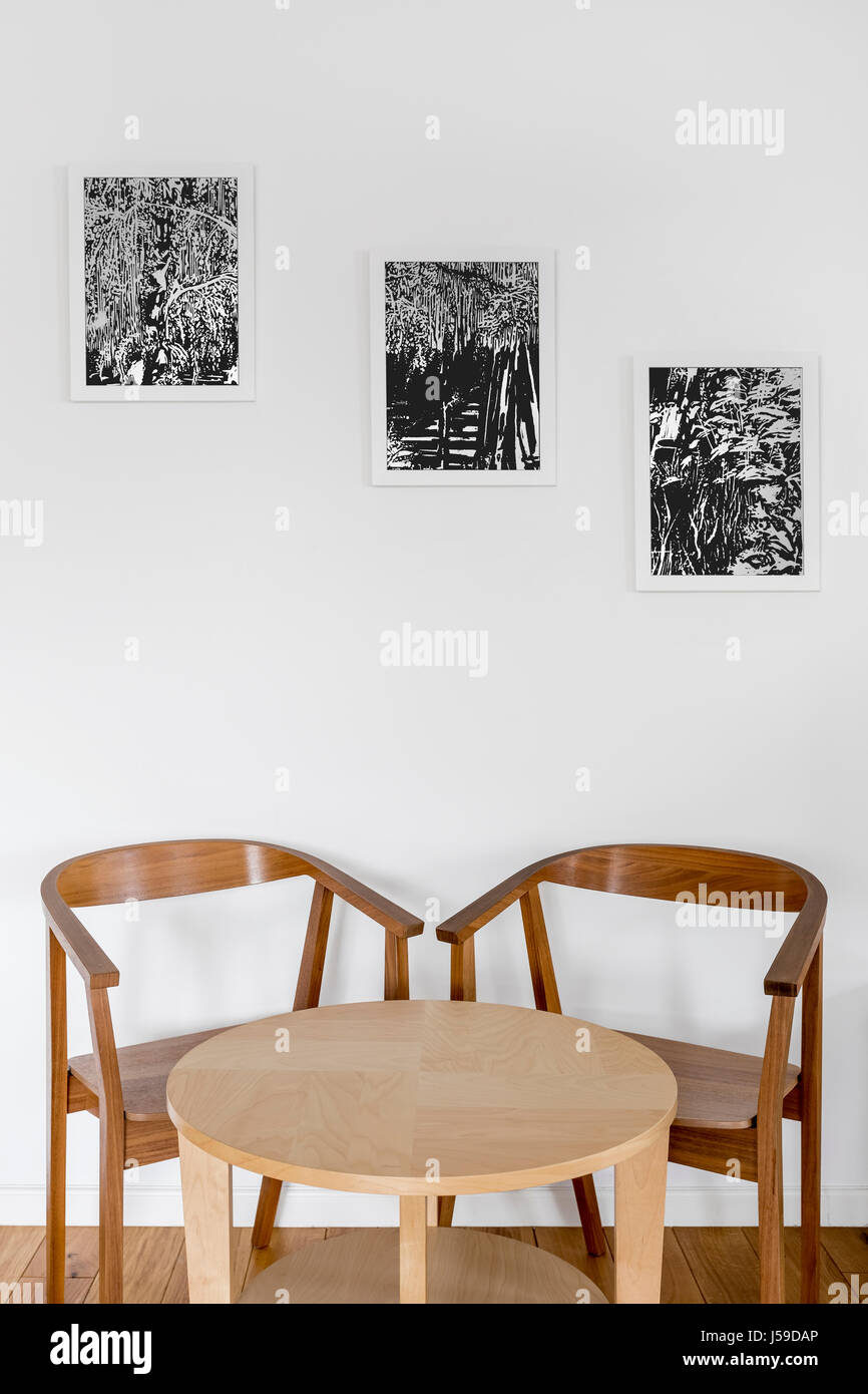 Vintage Holzstühle und Tisch im Zimmer mit modernen Kunstwerken Stockfoto