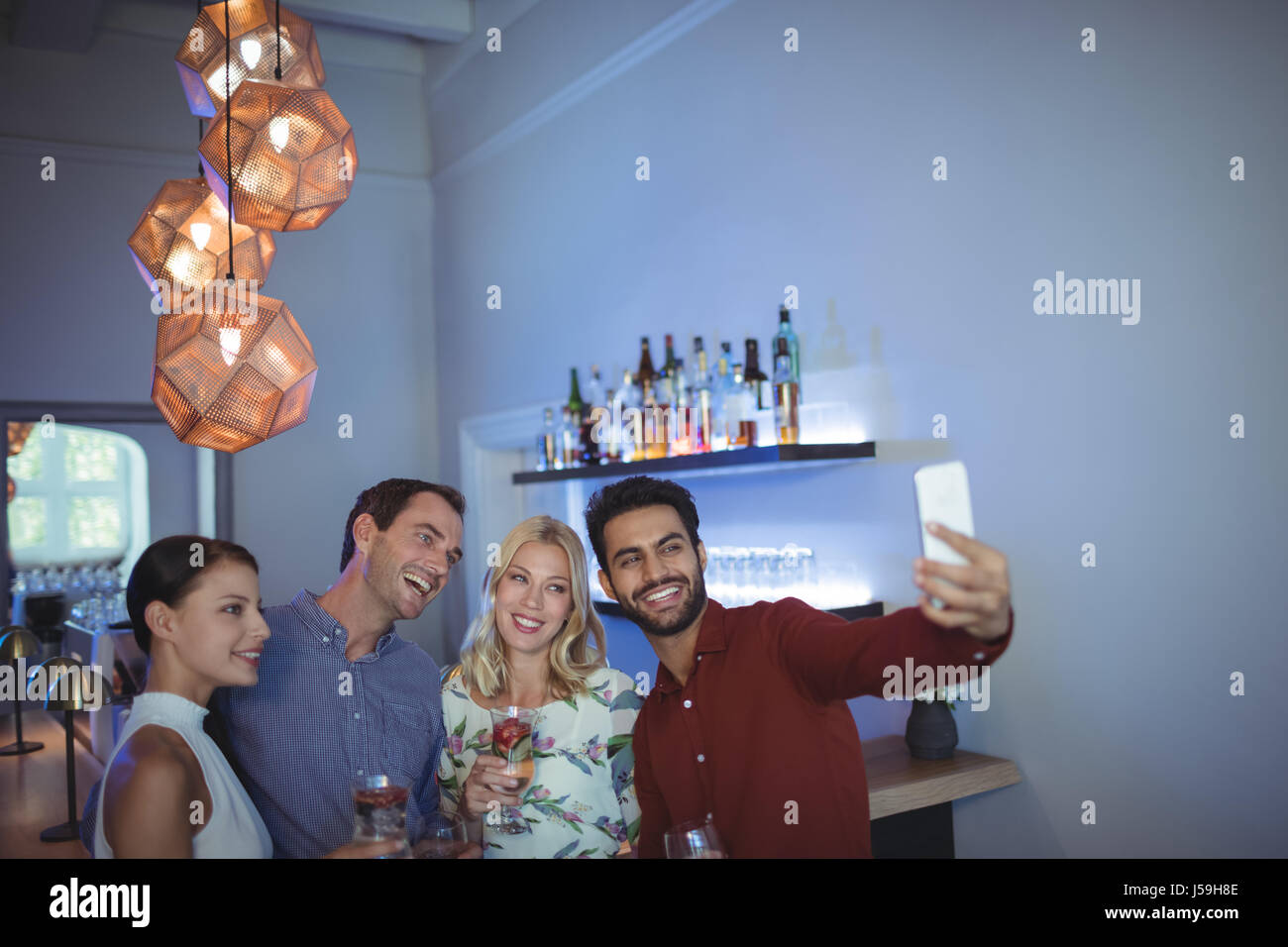Lächelnd zwei Paare posieren zusammen während des Gesprächs ein Selbstporträt im bar-restaurant Stockfoto