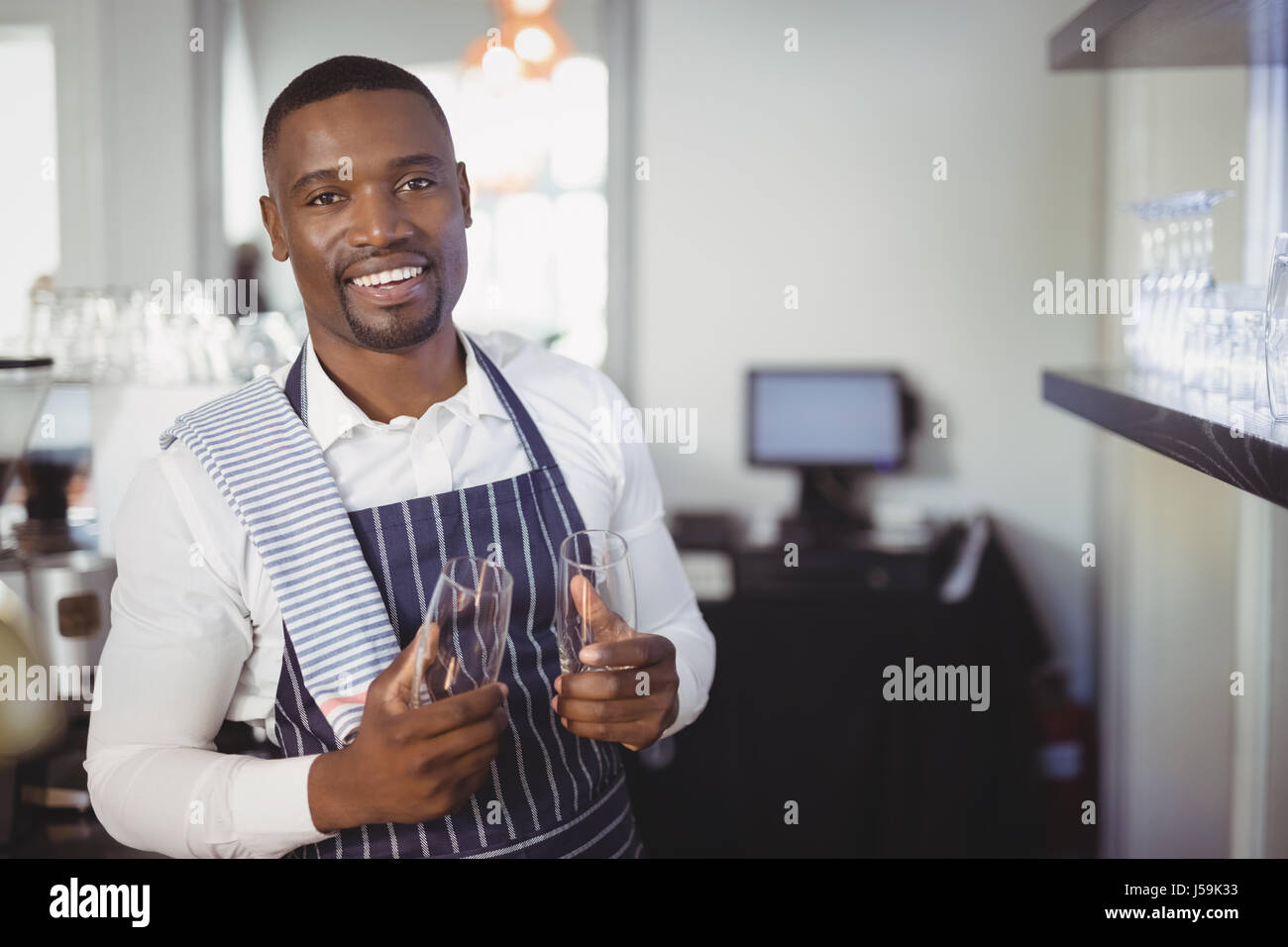 Porträt von lächelnden Kellner Holding Champagne Flute am Schalter im restaurant Stockfoto