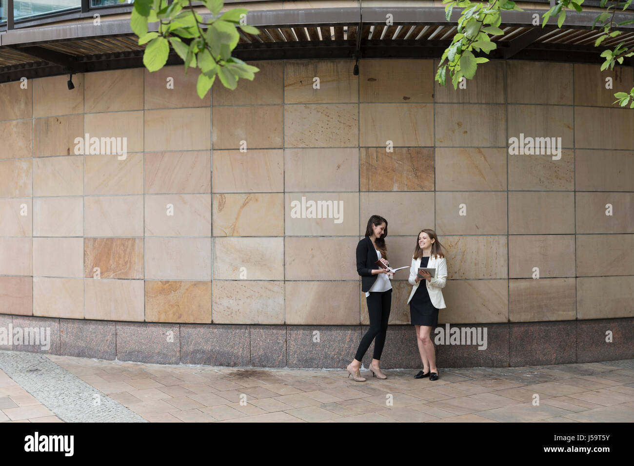 Zwei kaukasischen Geschäftsfrauen mit digitalen Tablettcomputer, Marmor Wand gelehnt. Stockfoto