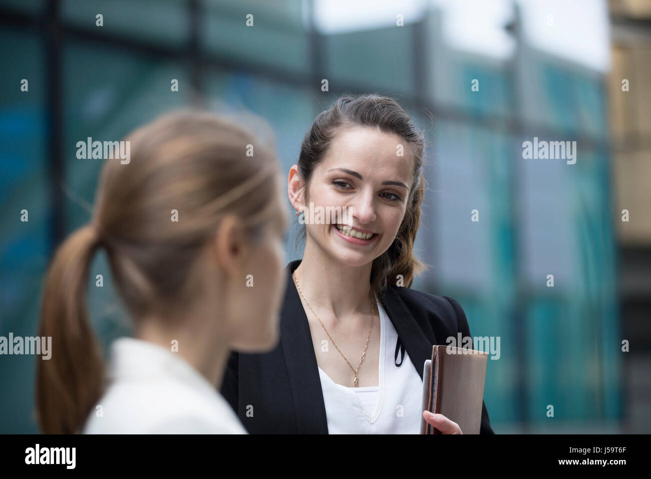 Porträt von zwei kaukasischen Geschäftsfrauen außerhalb modernen Büro Buidling sprechen. Stockfoto