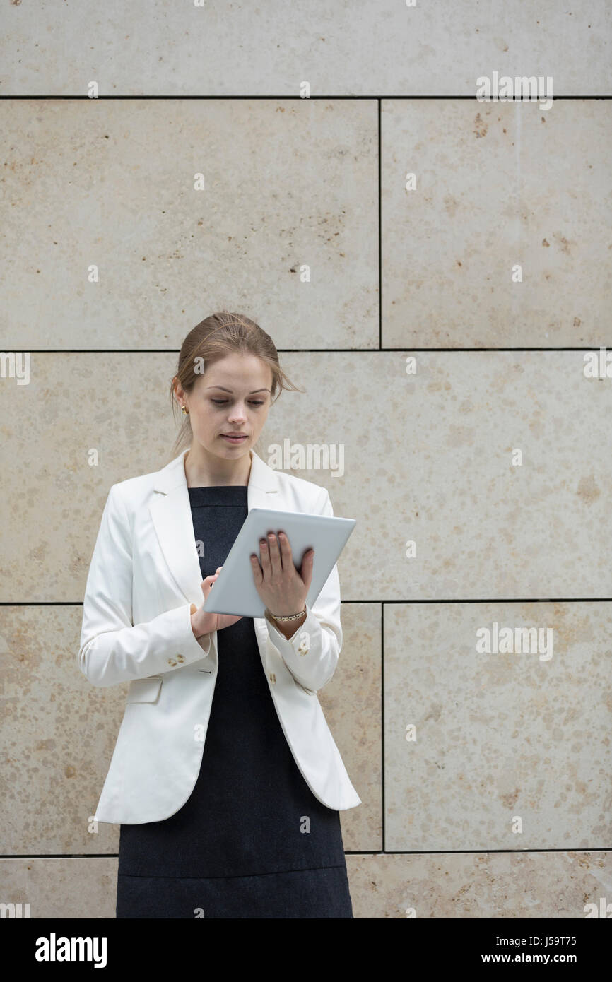 Kaukasische Geschäftsfrau mit digitalen Tablettcomputer, Marmor Wand gelehnt. Stockfoto