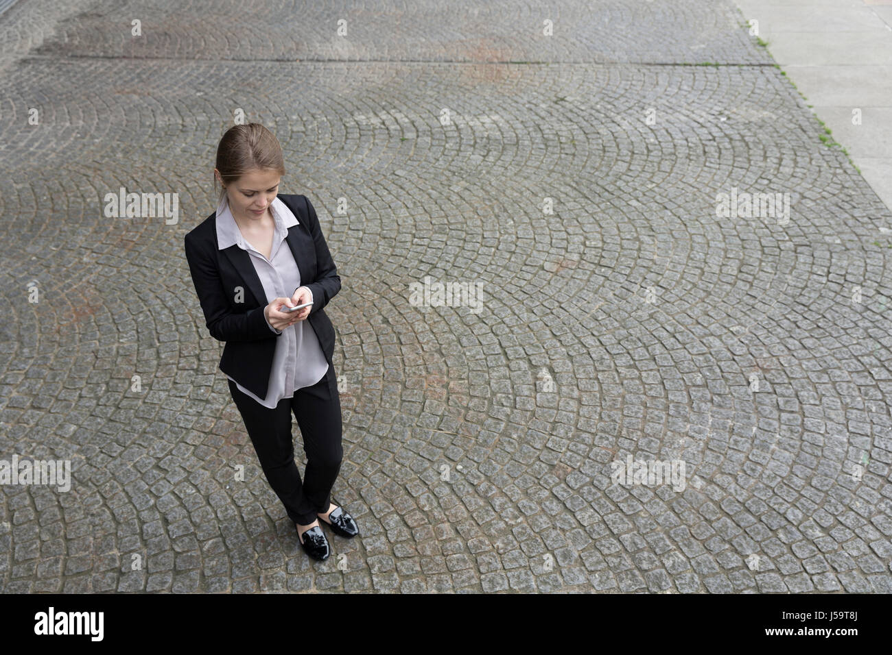 Erhöhten Blick auf eine Geschäftsfrau mit ihrem Smartphone. Business-Frau in modernen Stadt draußen. Stockfoto