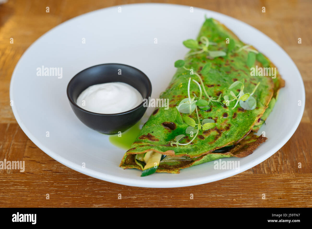Grüne Pfannkuchen mit Kräutern und Hanfsamen, gefüllt mit Käse und Gemüse. Vegane Küche Stockfoto