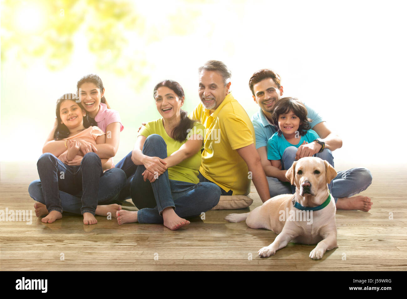 Porträt des mehr-Generationen-Familie mit Hund kniend auf Holzboden Stockfoto