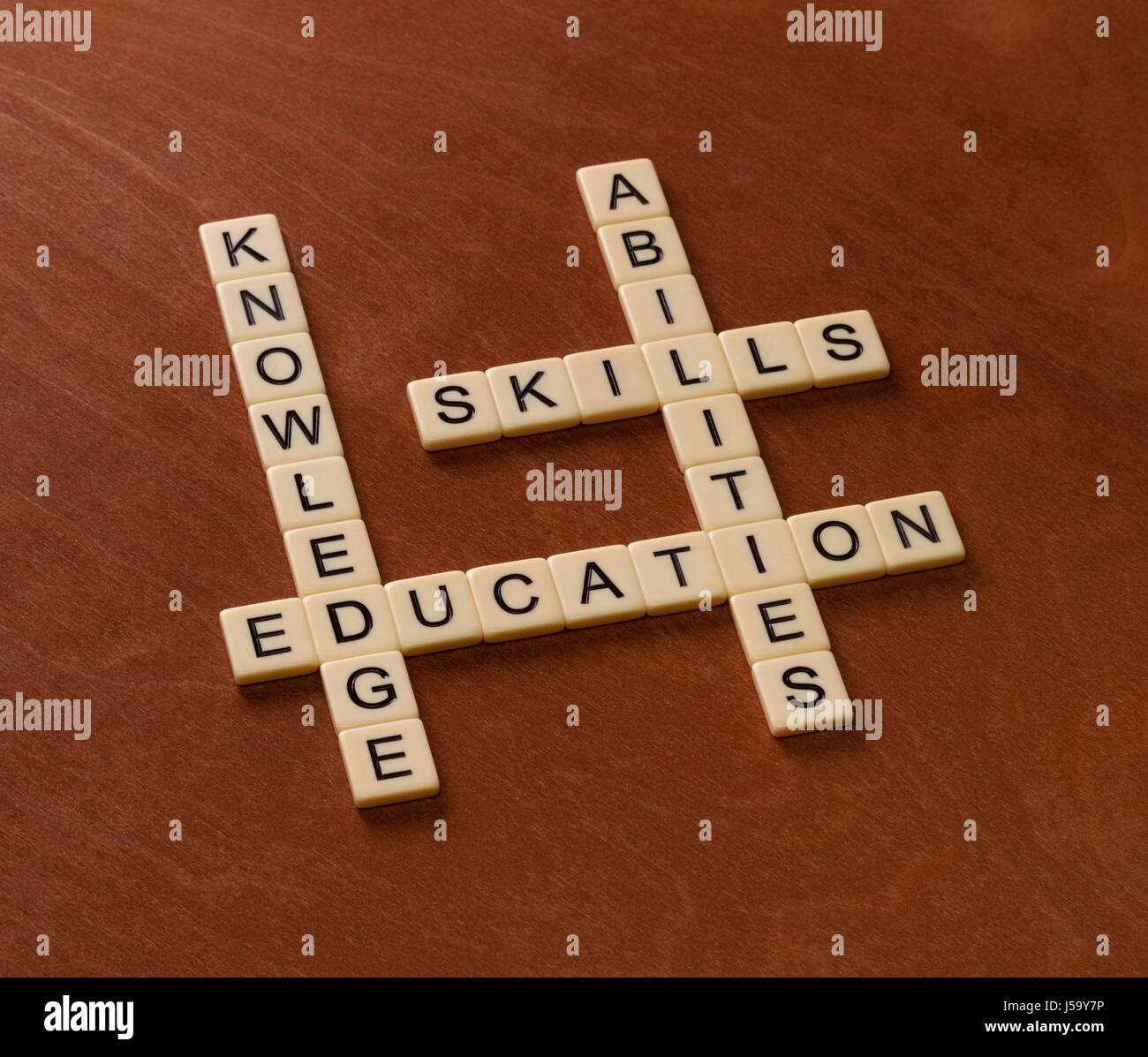 Kreuzworträtsel mit Worten Fertigkeiten, Fähigkeiten, wissen und Bildung. Learning-Konzepts. Elfenbein Fliesen mit Großbuchstaben auf Mahagoni Brett. Stockfoto