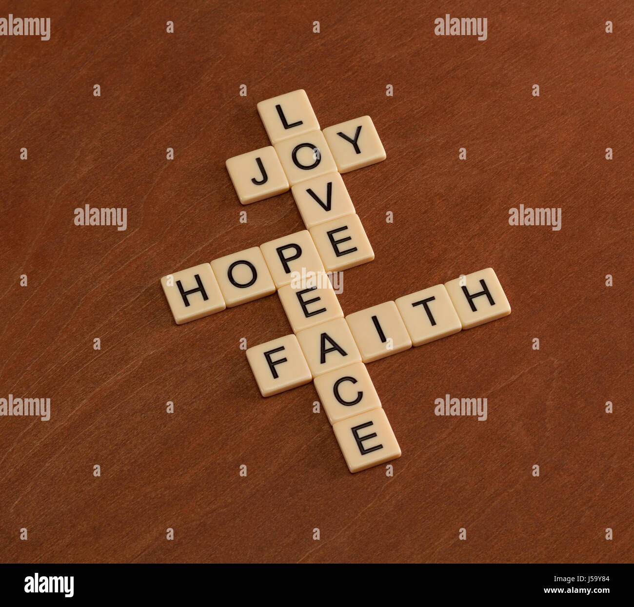 Kreuzworträtsel mit Worten glaube, Hoffnung, Liebe. Glaubens-Konzept. Elfenbein Fliesen mit Großbuchstaben auf Mahagoni Brett. Stockfoto