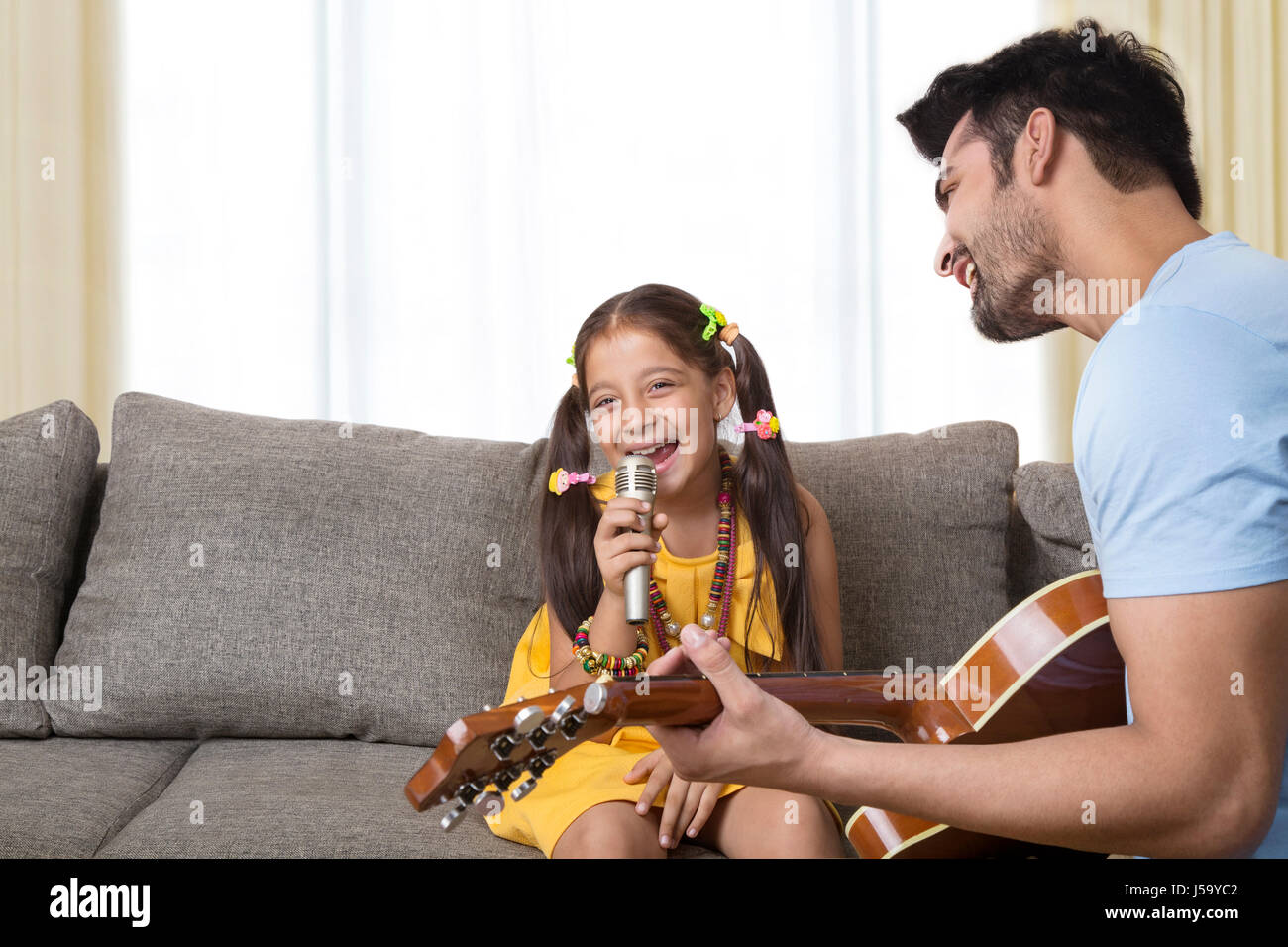 Vater spielt Gitarre und singt Tochter Stockfoto