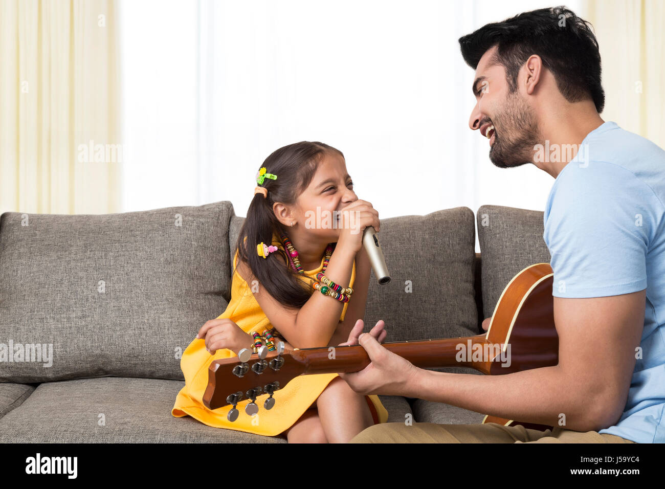 Vater spielt Gitarre und singt Tochter Stockfoto