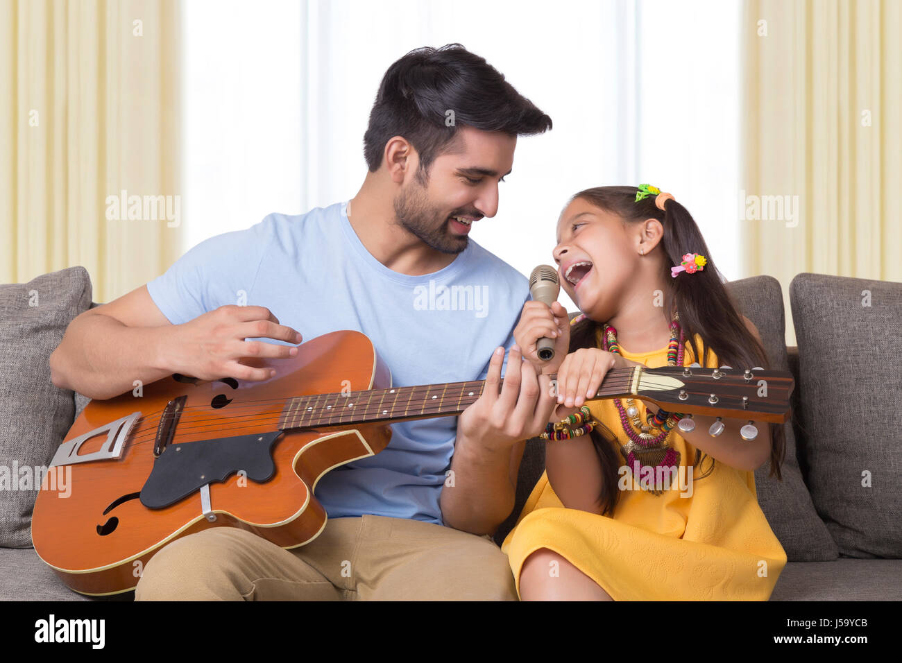 Vater spielt Gitarre und singt Tochter Stockfoto