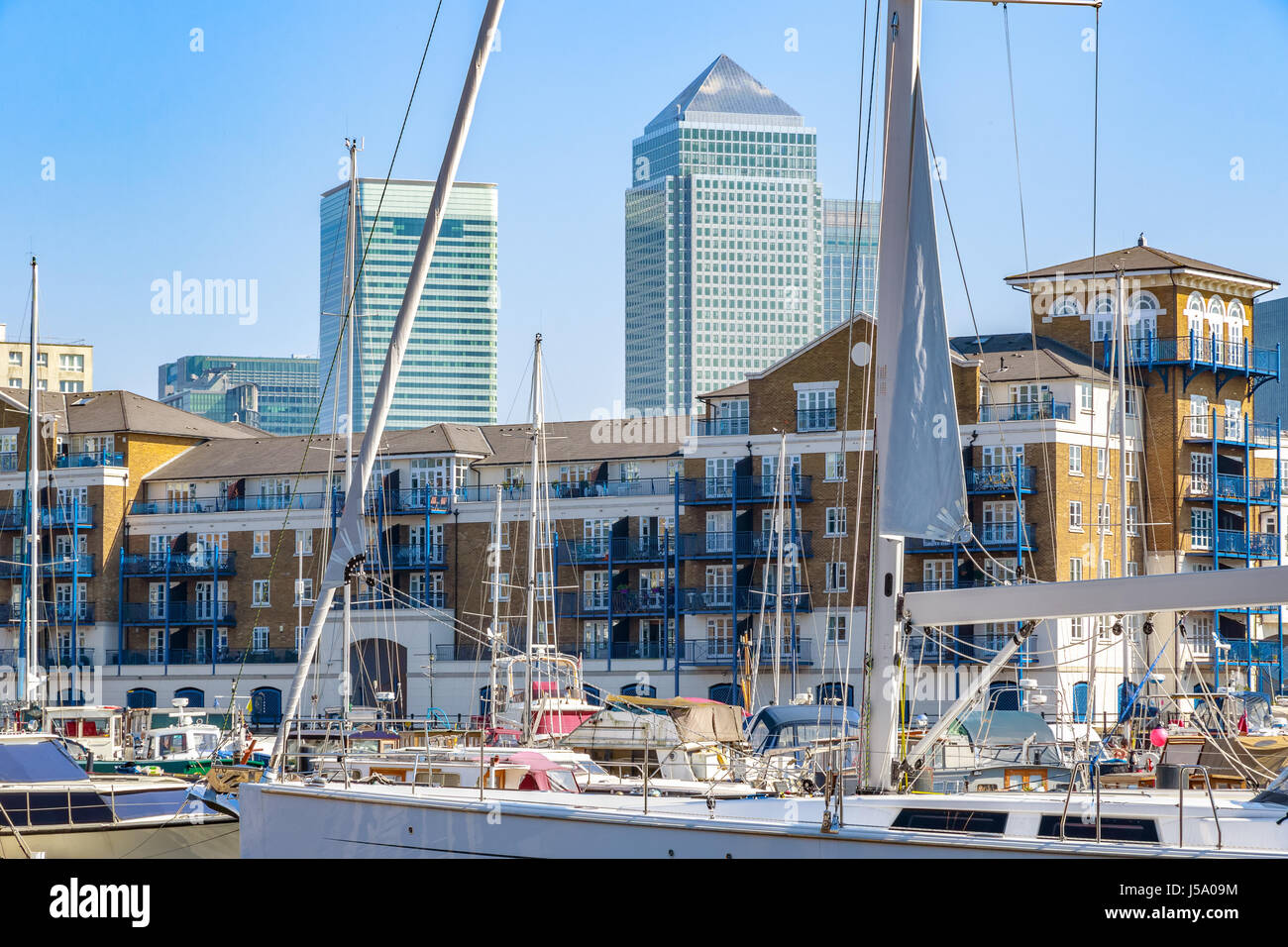 Boote und Yachten vor Anker in Limehouse Basin Marina in London mit Canary Wharf im Hintergrund Stockfoto