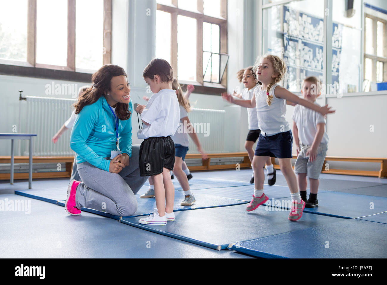 Kindergärtnerin, einer ihrer Schüler während einer Sportunterricht beruhigend. Stockfoto