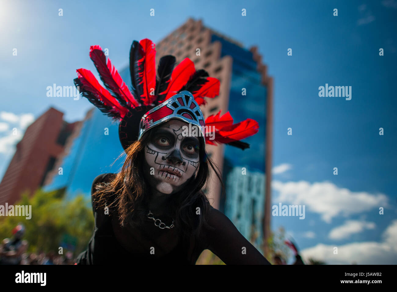 Ein mexikanisches Mädchen tragen eine Feder Kopfbedeckungen inspiriert von Azteken, tanzt auf der Straße während des Tages der Toten Prozession in Mexico City, Mexiko. Stockfoto