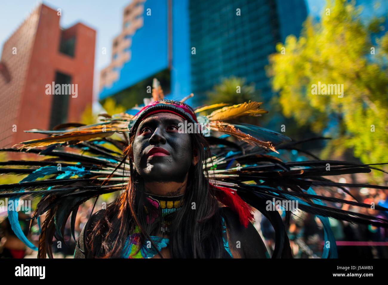 Ein mexikanisches Mädchen tragen eine bunte Feder Kopfbedeckungen inspiriert von Azteken, nimmt Teil am Tag der Toten feiern in Mexico City, Mexiko. Stockfoto