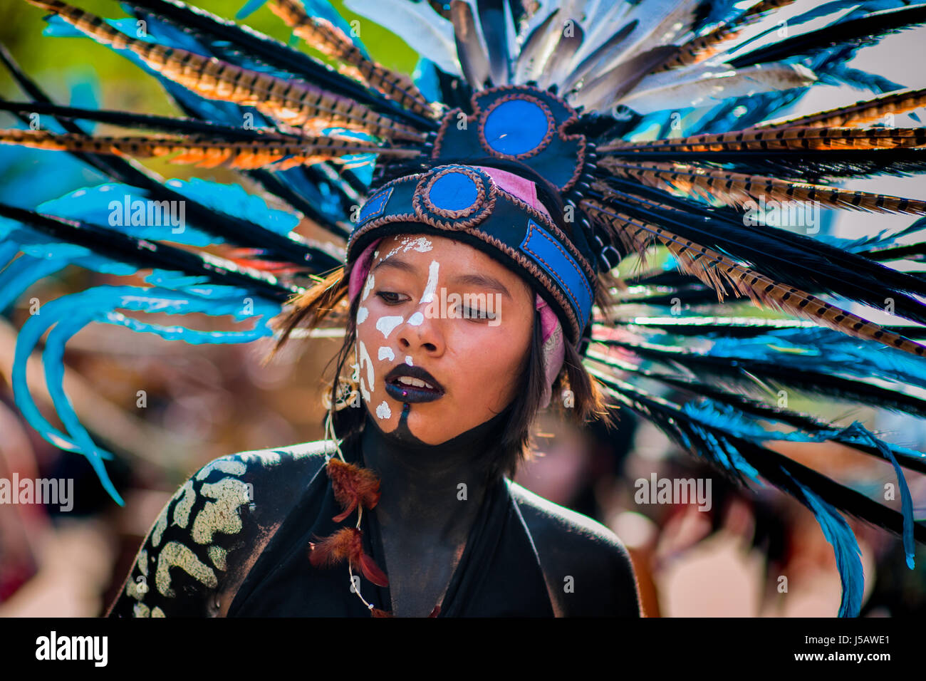 Ein mexikanisches Mädchen tragen eine große Feder Kopfbedeckungen inspiriert von Azteken, nimmt Teil am Tag der Toten feiern in Mexico City, Mexiko. Stockfoto