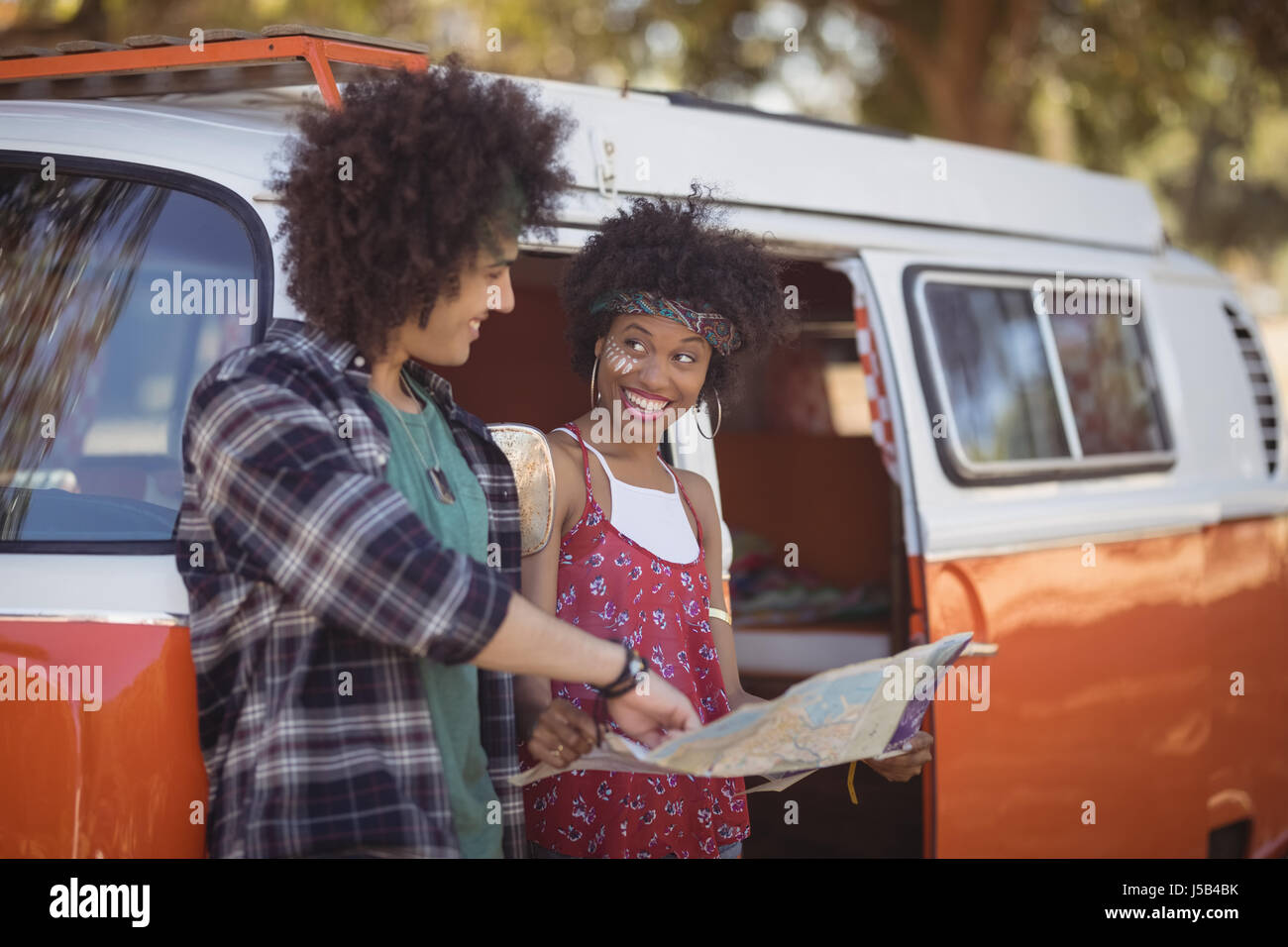 Lächelnde Frau mit Blick auf Menschen mit einem geparkten Kleinbus Karte Stockfoto