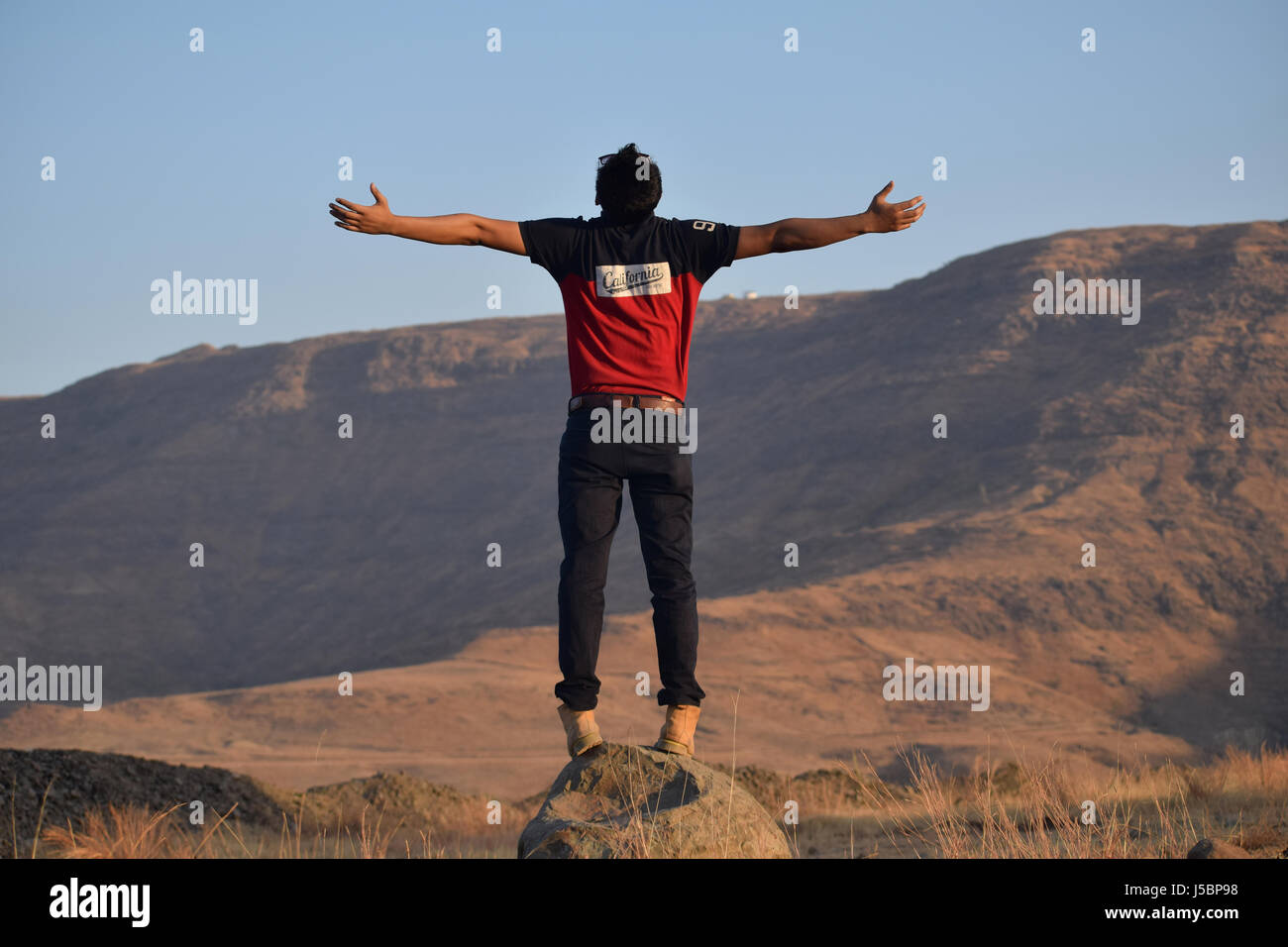 Junger Mann mit ausgestreckten Händen in der Nähe von Berg, Pune, Maharashtra Stockfoto