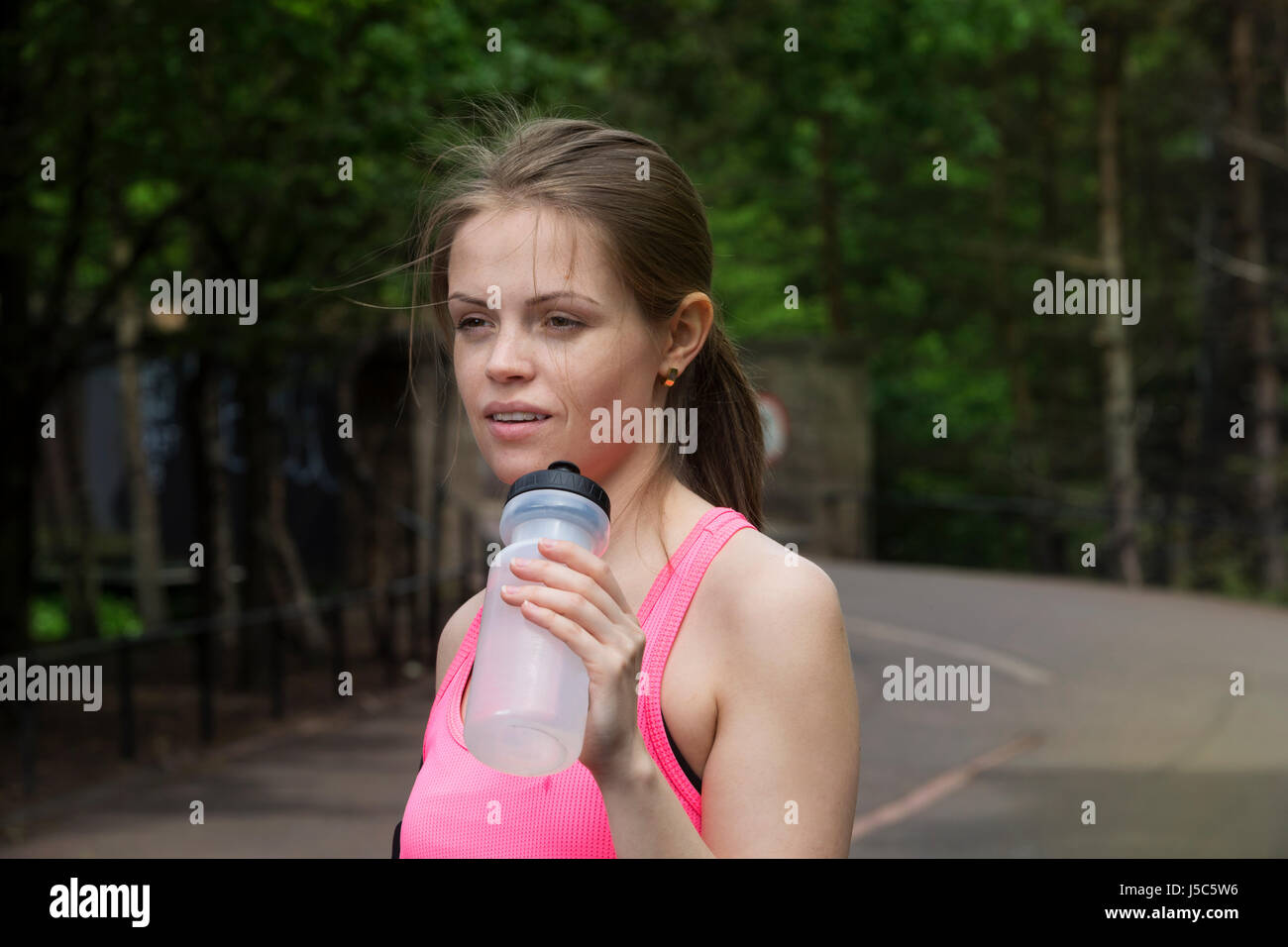 Sportliche Frau Trinkwasser, während Training draußen in einer natürlichen Umgebung. Aktion und gesunden Lifestyle-Konzept. Stockfoto