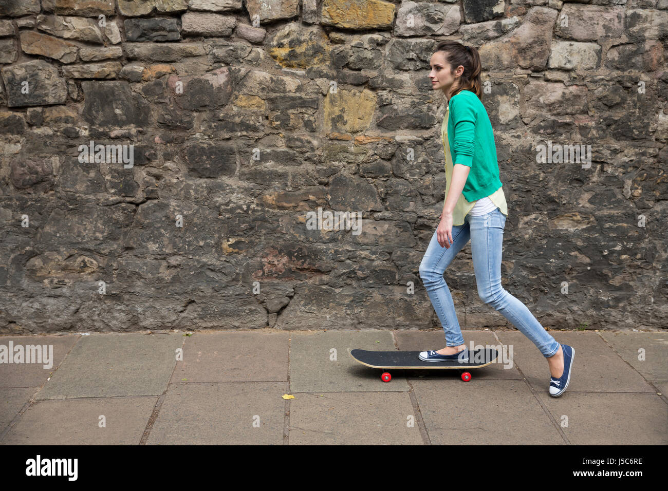 Porträt einer jungen Frau skaten entlang einer Stadtstraße. Stockfoto