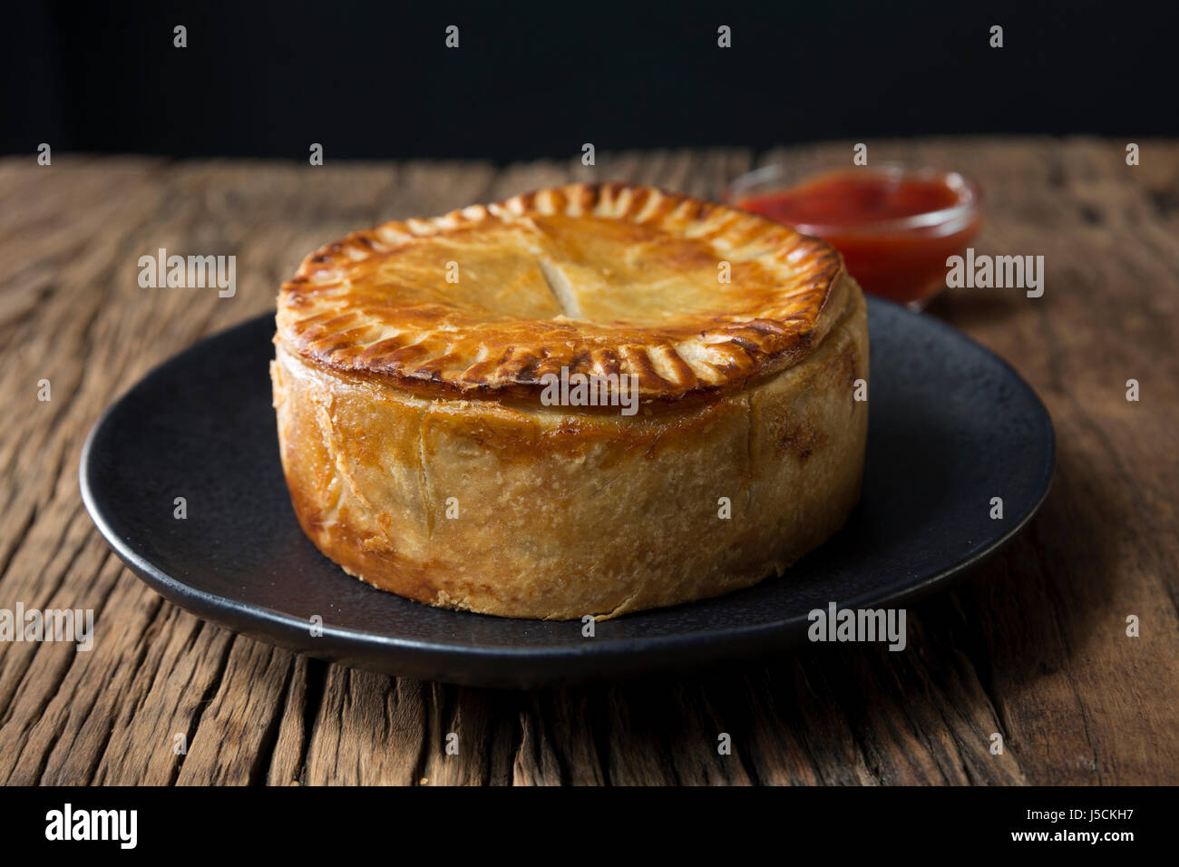 Ein traditionelles britisches Fleisch Pie sitzen auf einem rustikalen Holztisch. Stockfoto