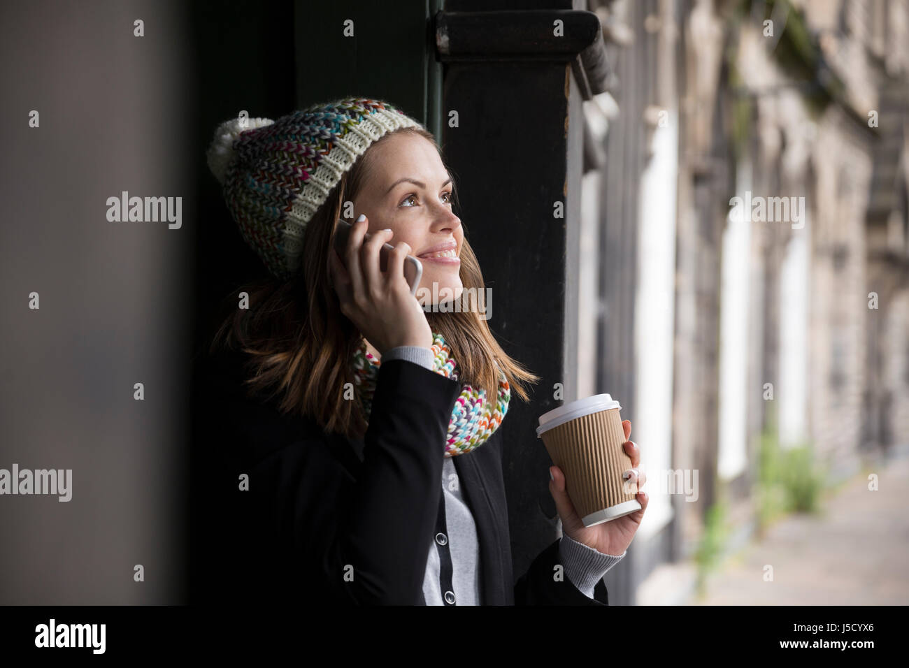 Kaukasische Frau lehnt in einer Tür Weg und auf einem Smartphone sprechen. Im Freien in der Stadt. Stockfoto