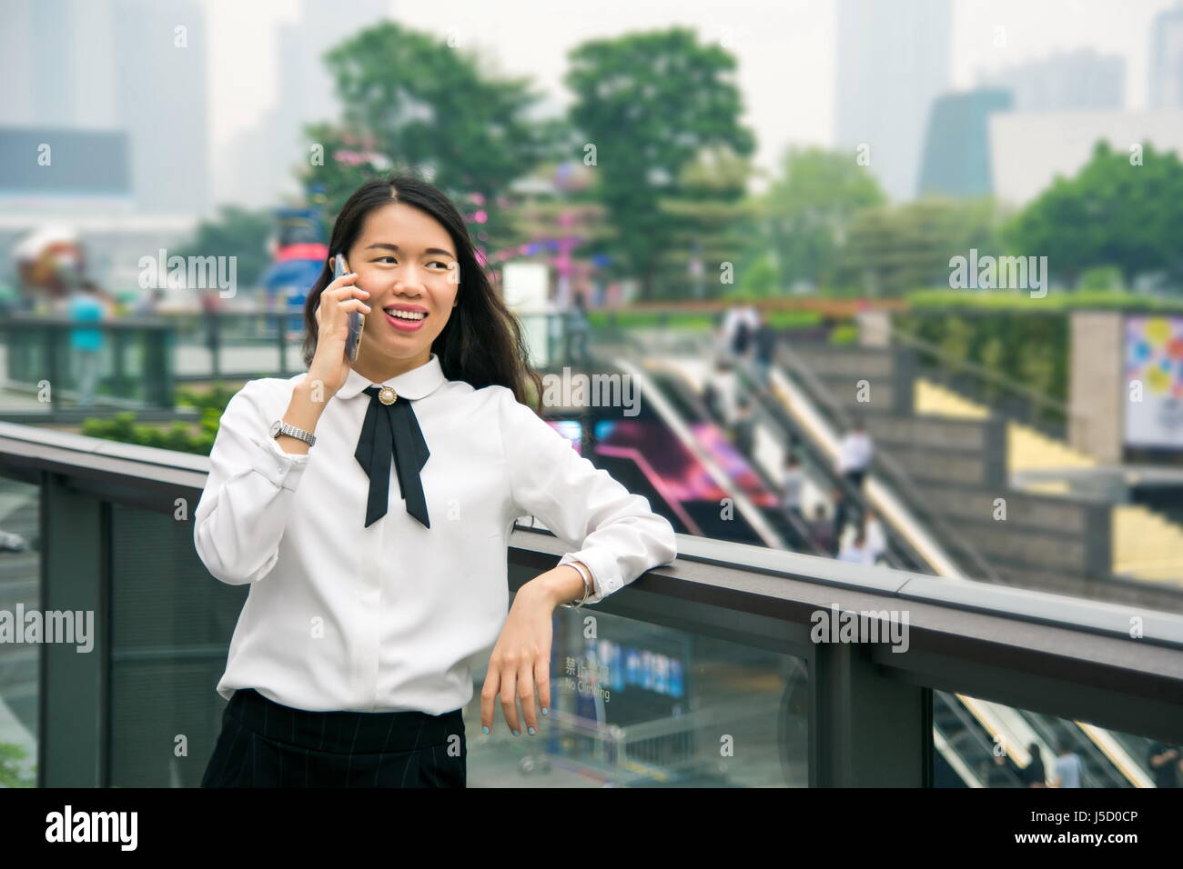 Business-Frau am Telefon in moderner Umgebung außerhalb Stockfoto