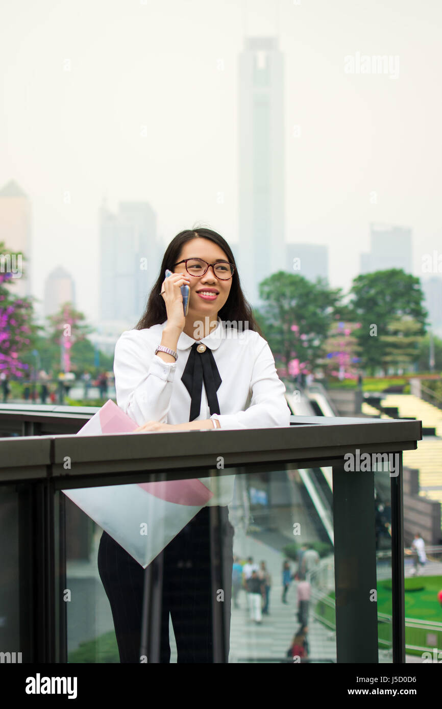 Business-Frau am Telefon in moderner Umgebung außerhalb Stockfoto