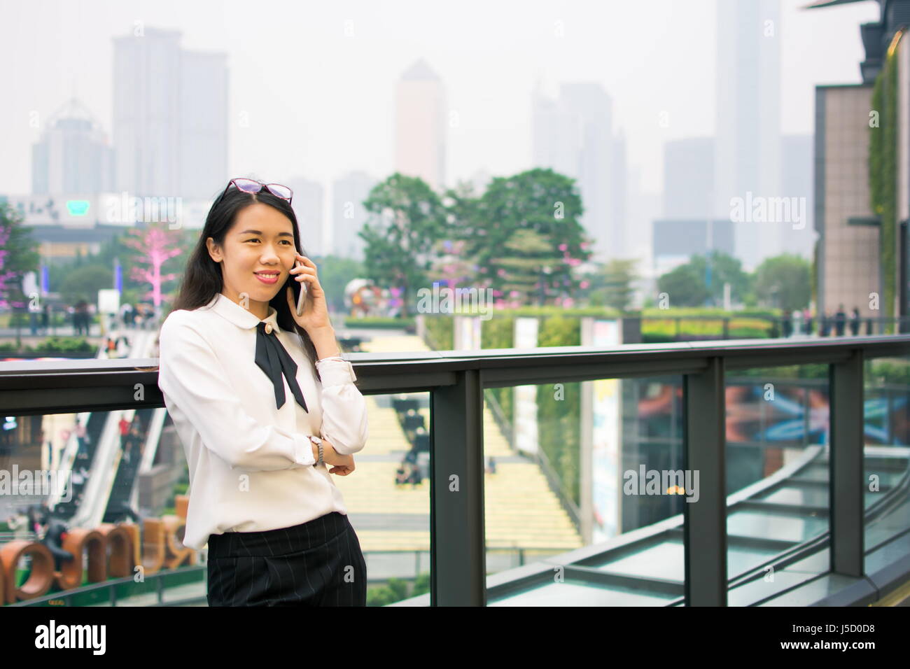 Business-Frau mit Telefon, umgeben von modernen Hochhäusern Stockfoto