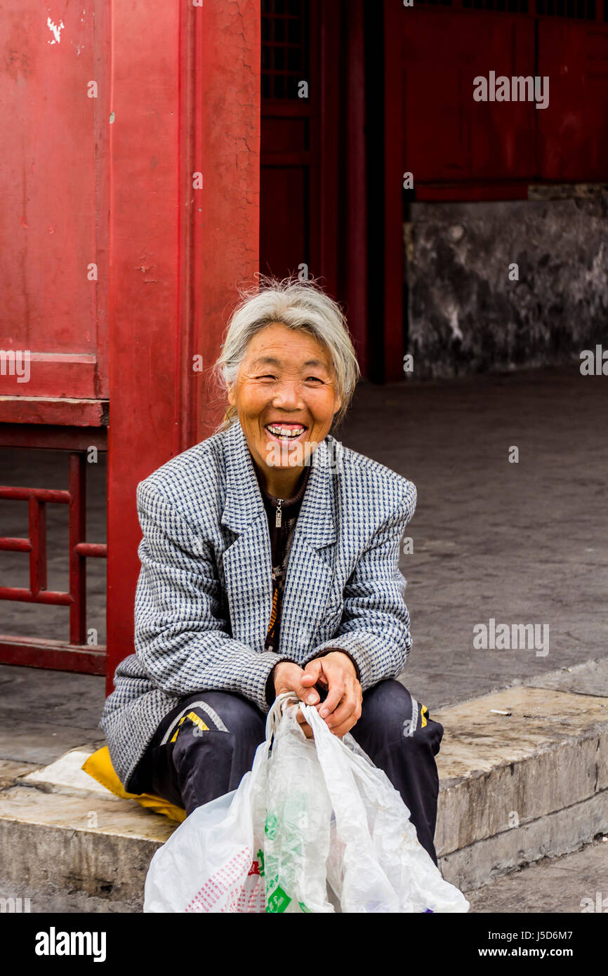 BEIJING, CHINA 26. März 2014:-die alte Dame ruht neben einer roten Wand außerhalb der verbotenen Stadt Stockfoto