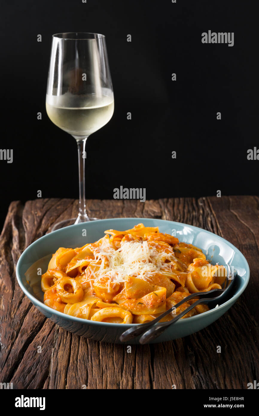 Pasta mit Meeresfrüchten mit Tomatensauce und Parmesan. Auf einem rustikalen Holztisch sitzend. Stockfoto