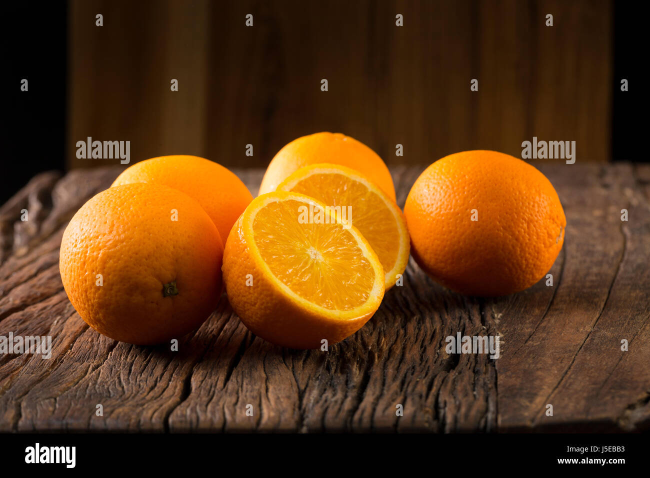 Ein Bunc Orangen auf einem rustikalen Holztisch sitzend. Stockfoto