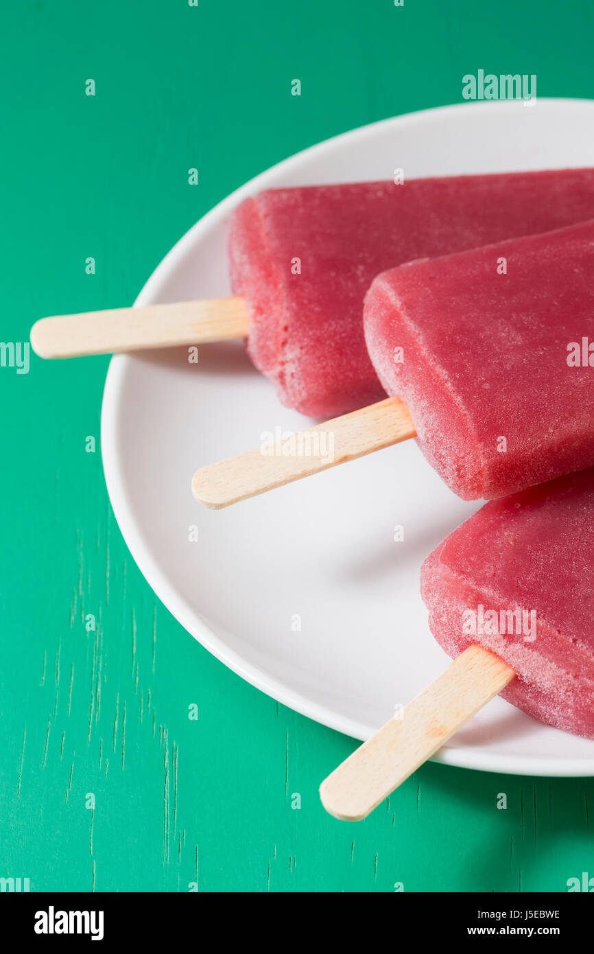 3 hausgemachte Himbeeren und Vanilleeis öffnet auf grünem Holz Hintergrund. Berry Eis Eis am Stiel. Sommer essen. Stockfoto