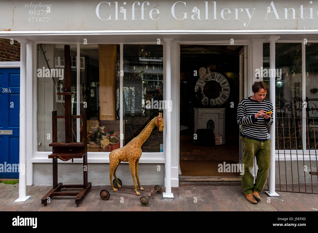 Ein Mann steht vor einem Antiquitäten Shop SMS auf ein Smartphone, High Street, Lewes, Sussex, UK Stockfoto