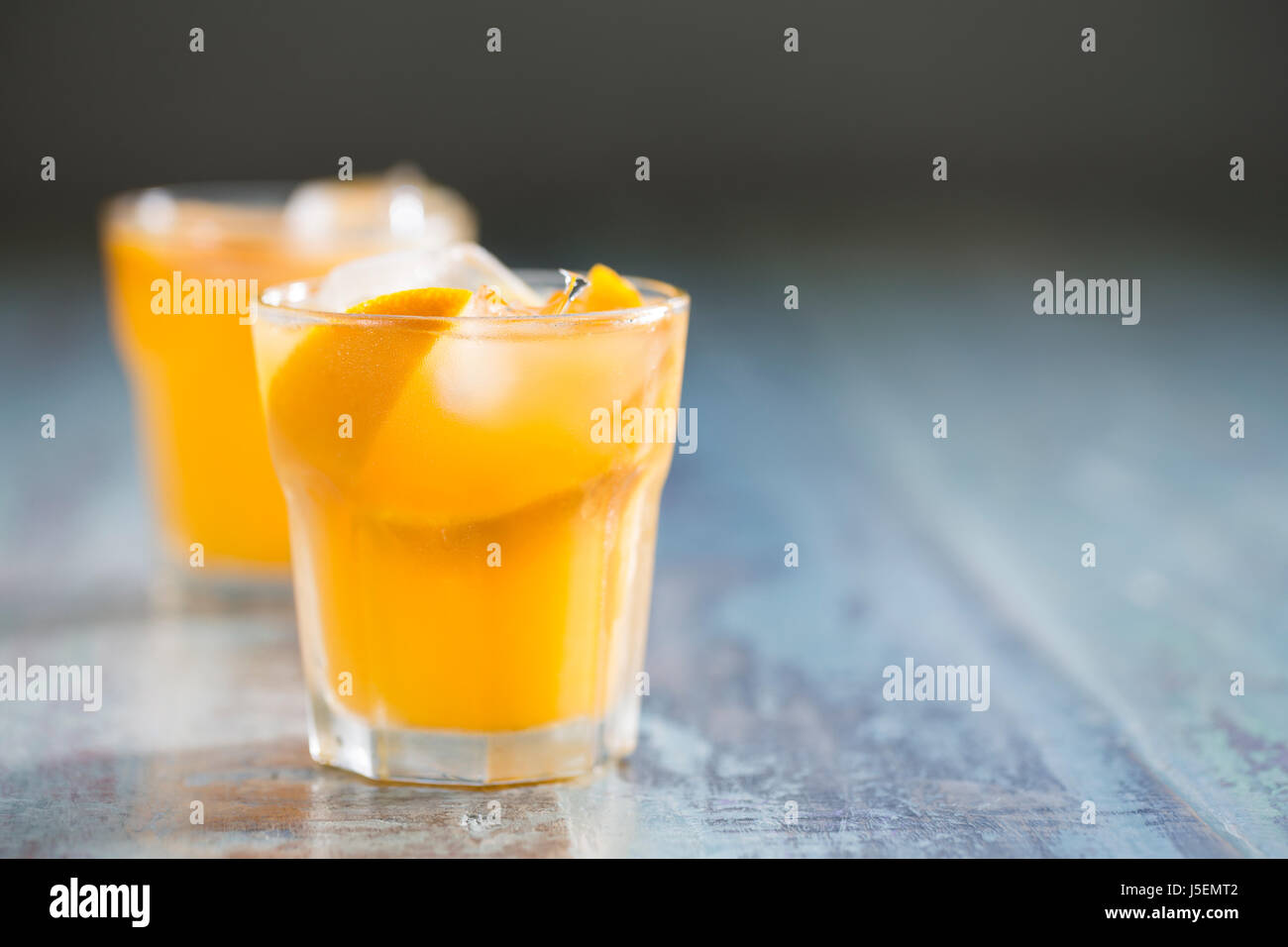 Frisch gepresster Orangensaft auf einem rustikalen Holztisch sitzend. Stockfoto