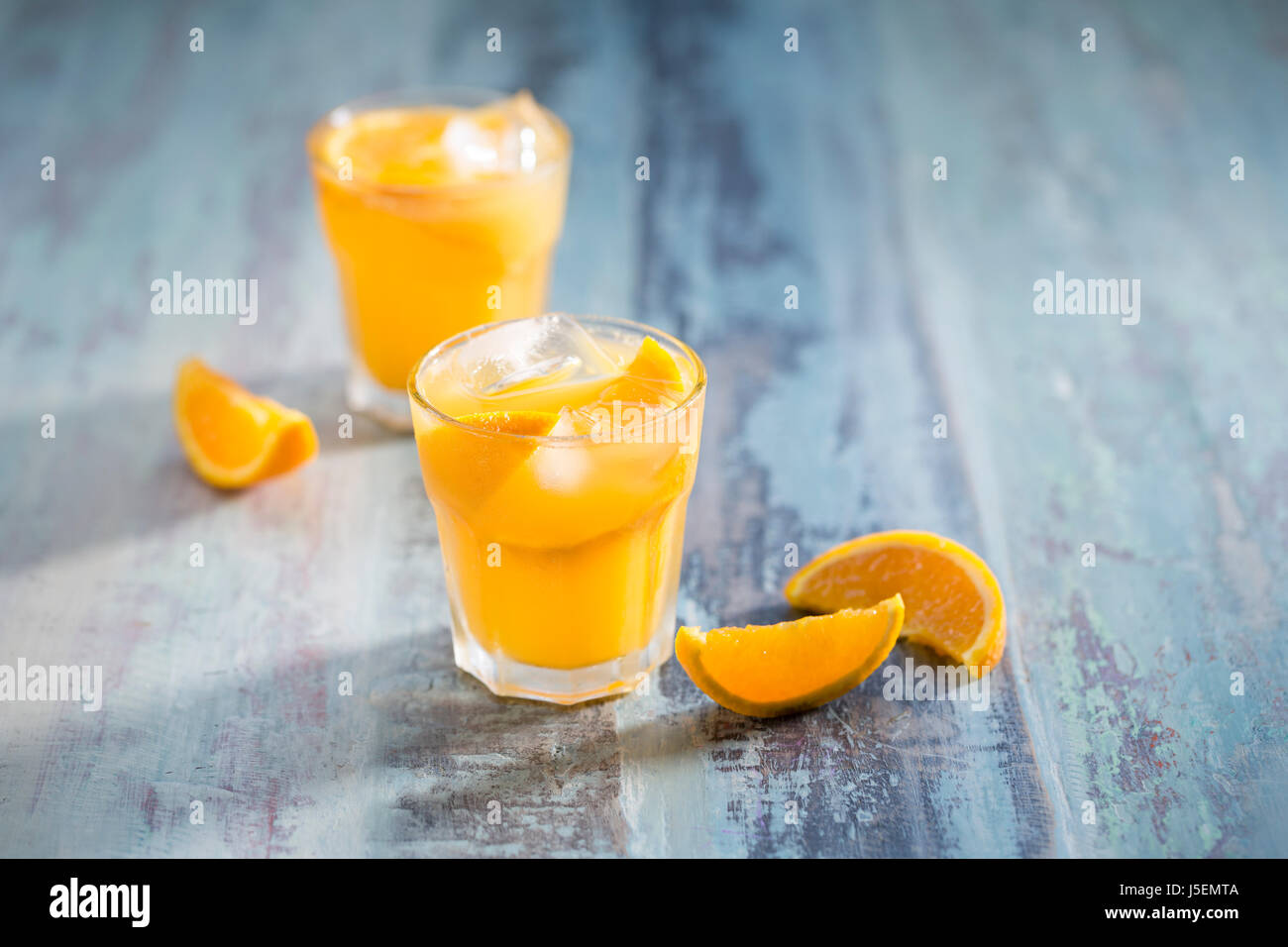Frisch gepresster Orangensaft auf einem rustikalen Holztisch sitzend. Stockfoto