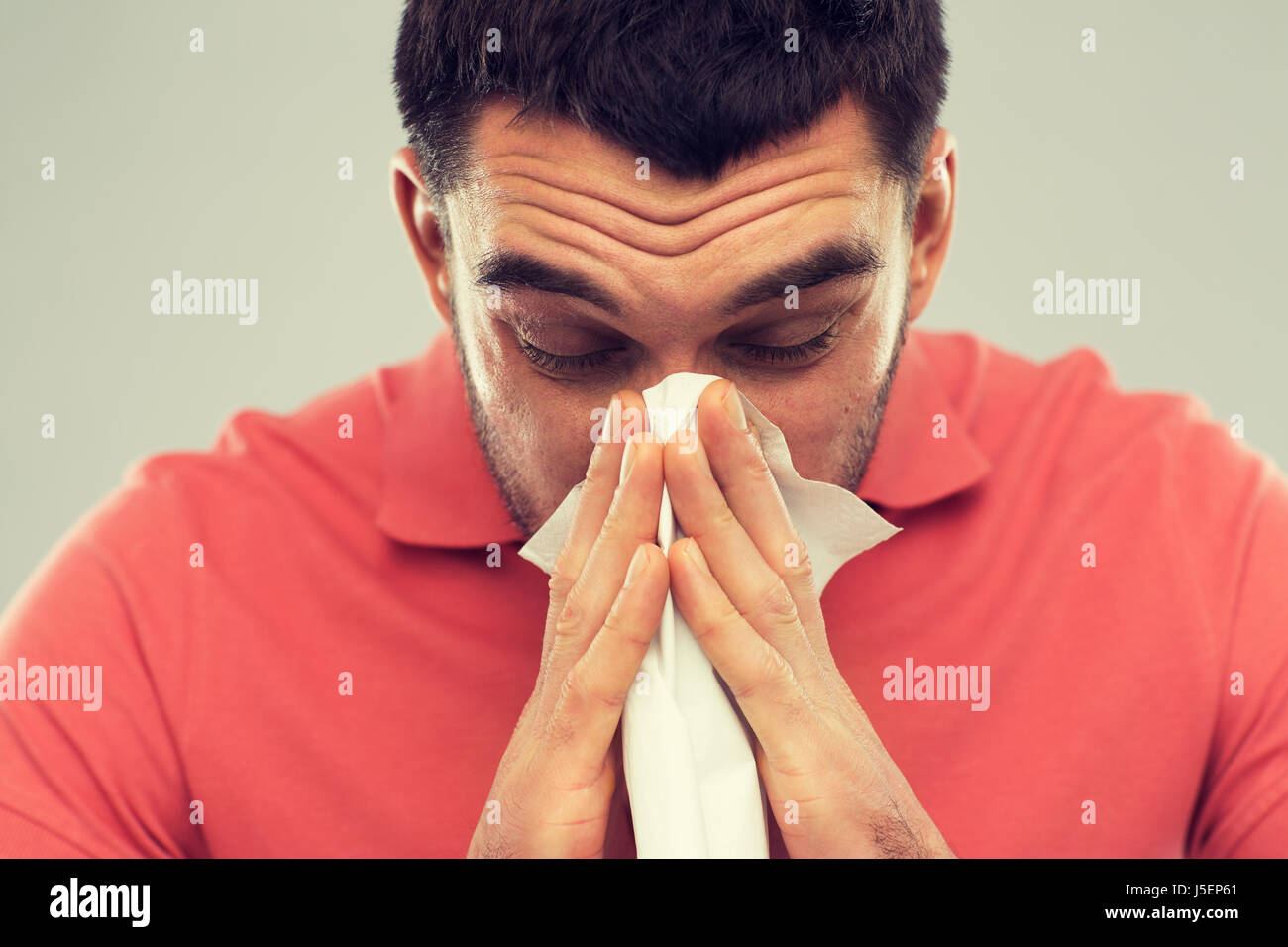 kranker Mann bläst Nase zu Papierservietten zu Hause Stockfoto