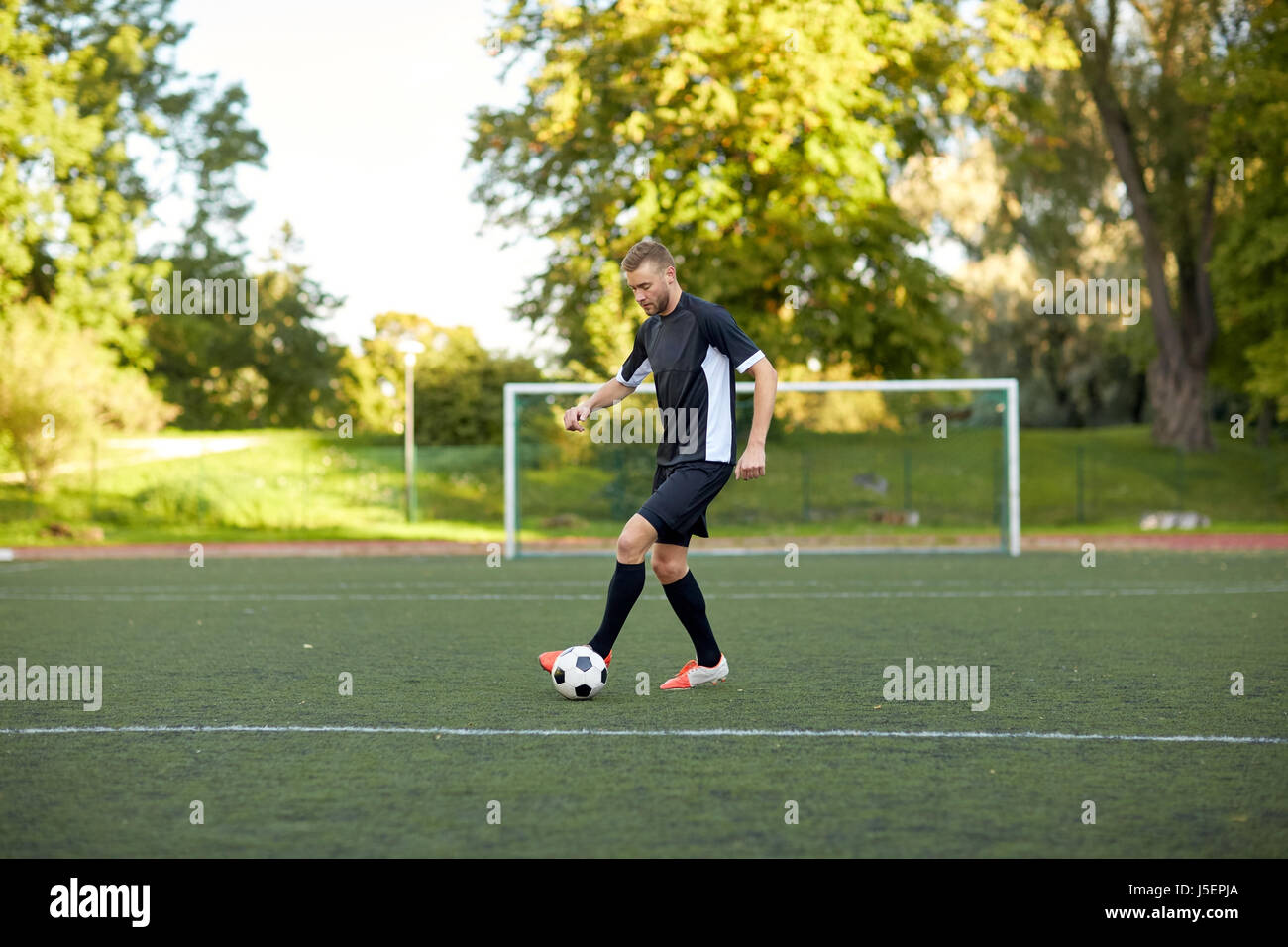 Fußballspieler mit Ball auf Fußballplatz spielen Stockfoto